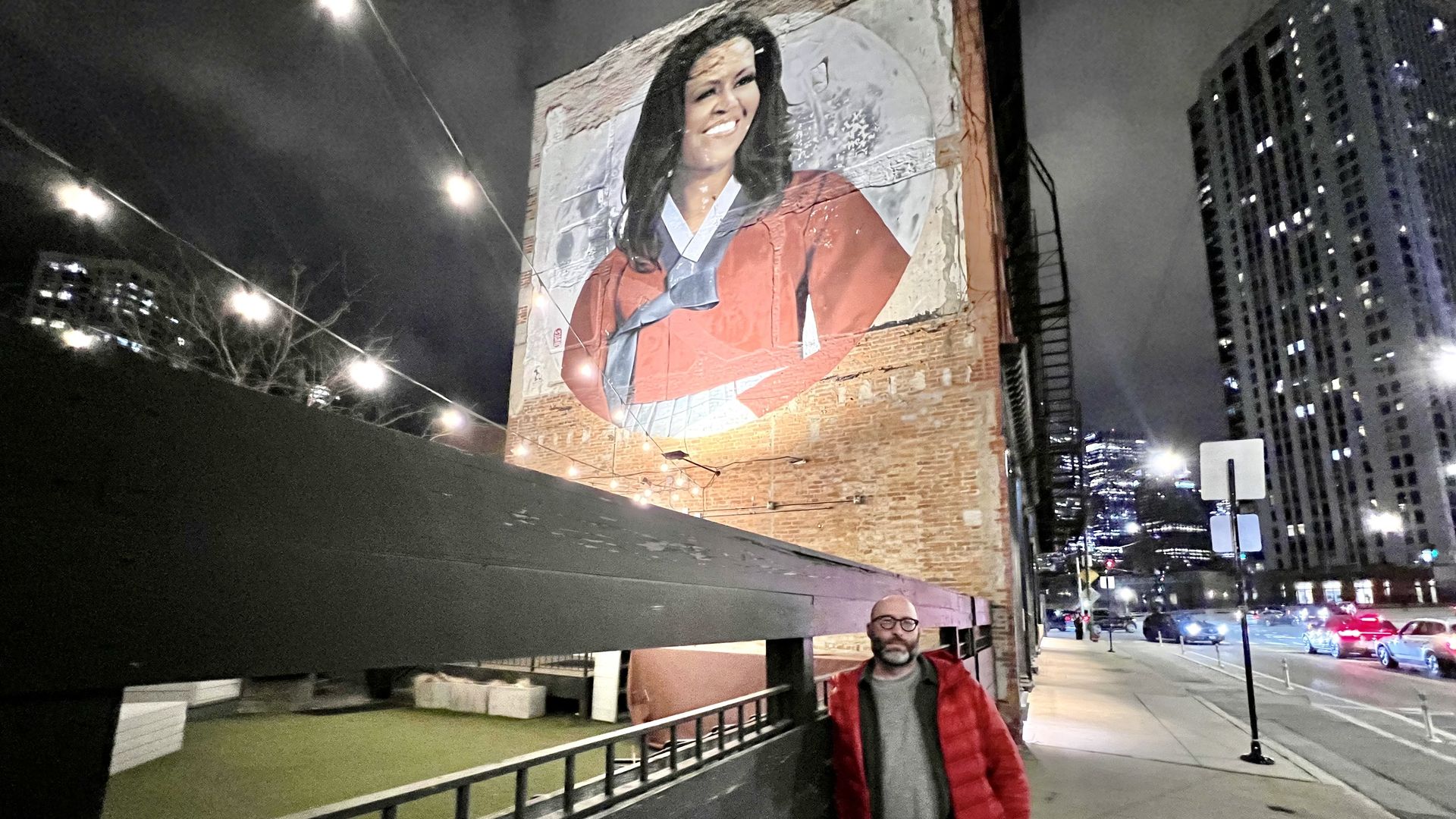 Photo of a man standing in front of a mural 
