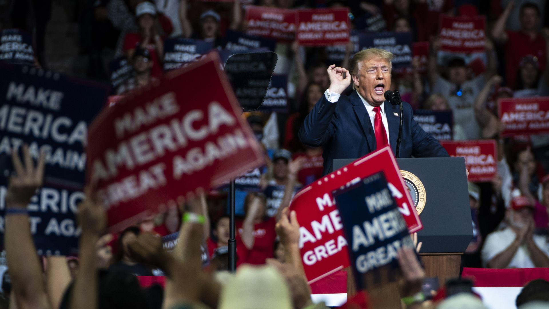 President Trump speaking at a rally in Tulsa as people wave "Make America Great Again" signs