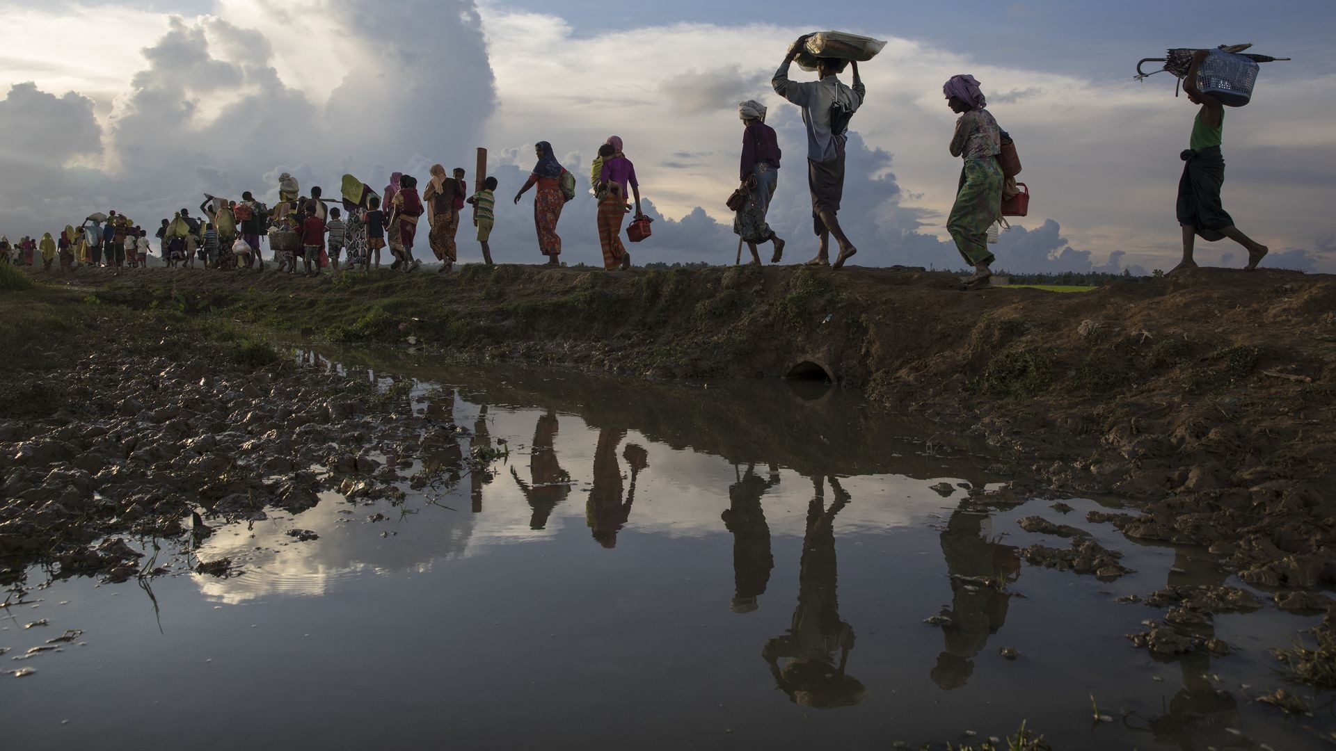 Thousands of Rohingya refugees fleeing from Myanmar walk along a muddy rice field after crossing the border in Palang Khali, Cox's Bazar, Bangladesh in 2017.