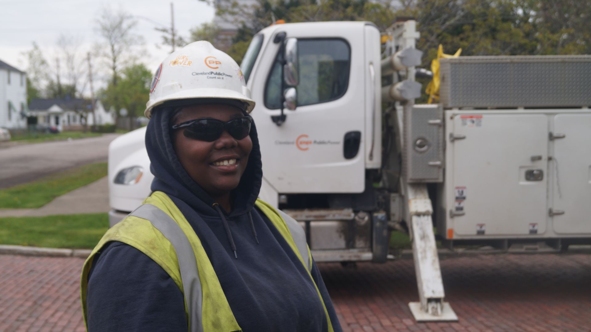 A helmeted Ta'Jahne Buchanan poses before a Cleveland Public Power truck on a brick street.