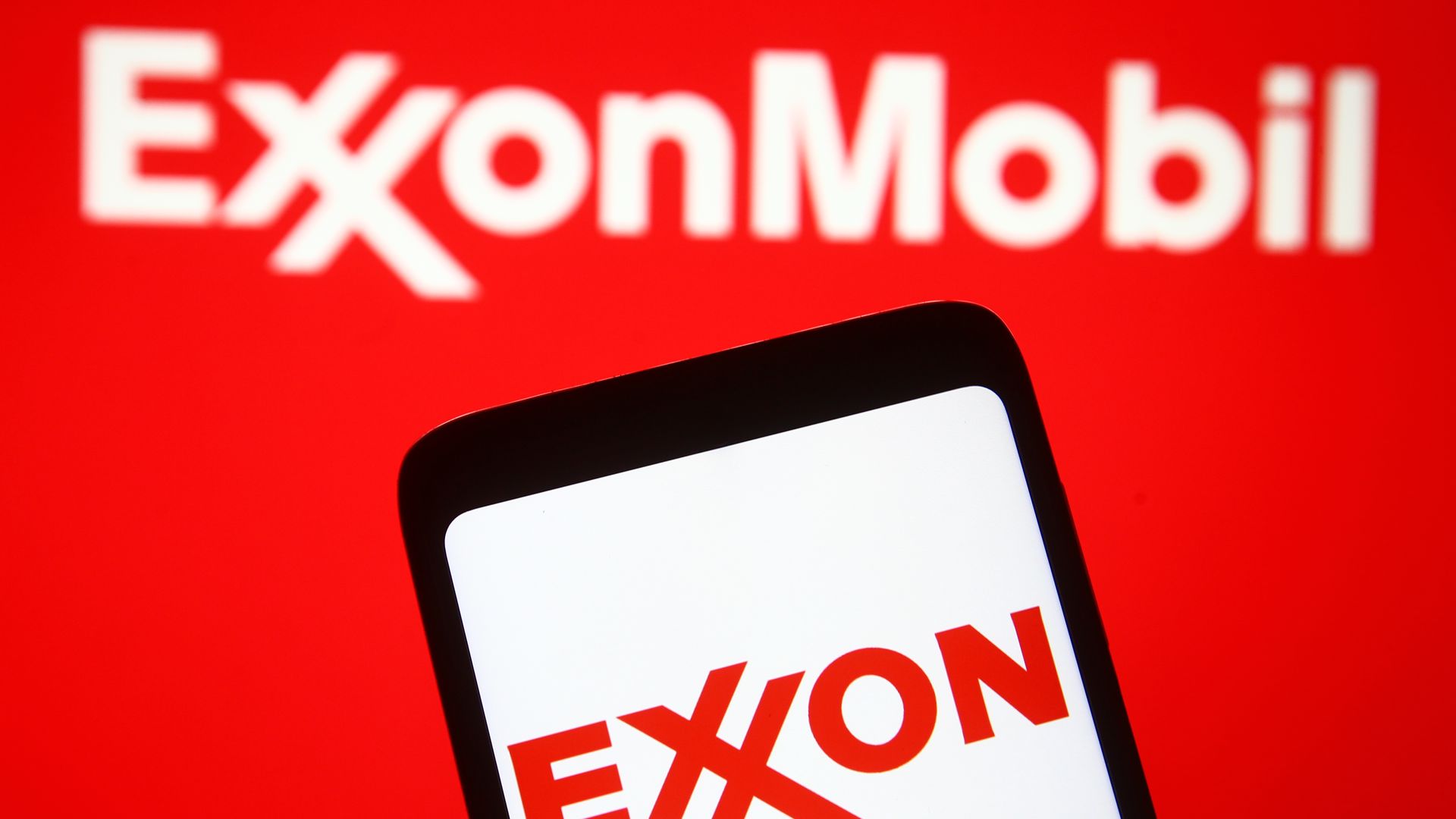 Photo illustration with the Exxon Mobil logo is displayed on a smartphone and a pc screen. 
