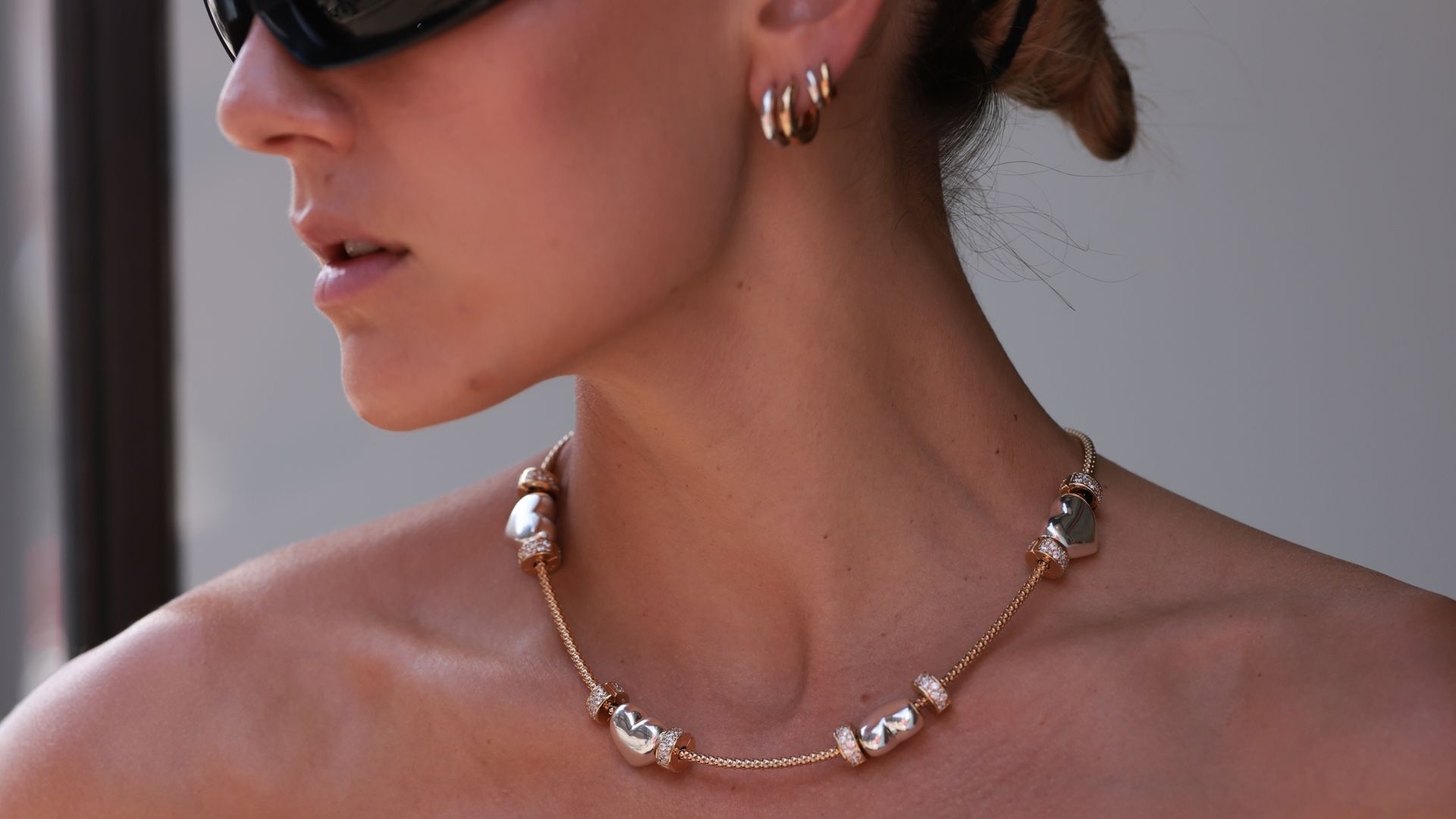 A woman wearing gold earnings and a gold necklace.