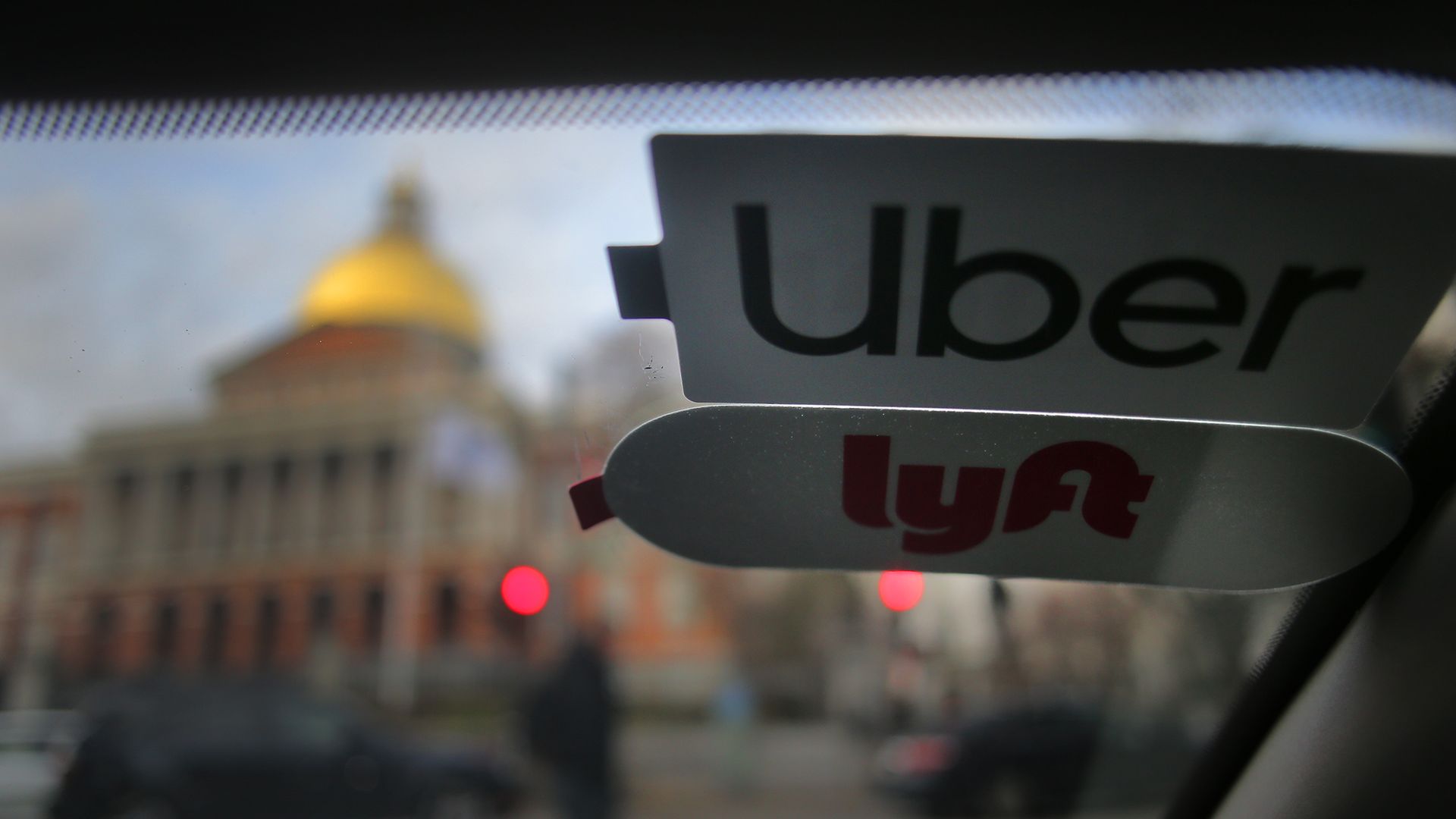 Photo from inside a car's passenger seat with Uber and Lyft stickers in the windshield