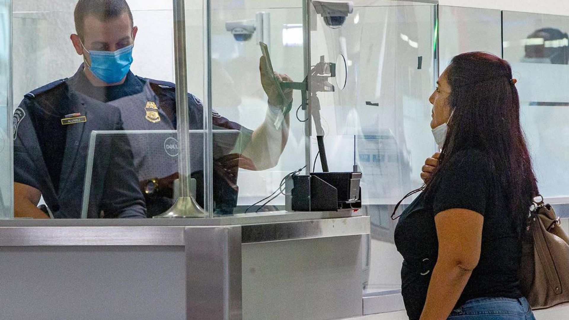 A US customs and border agent takes a photograph of a traveler using facial recognition technology