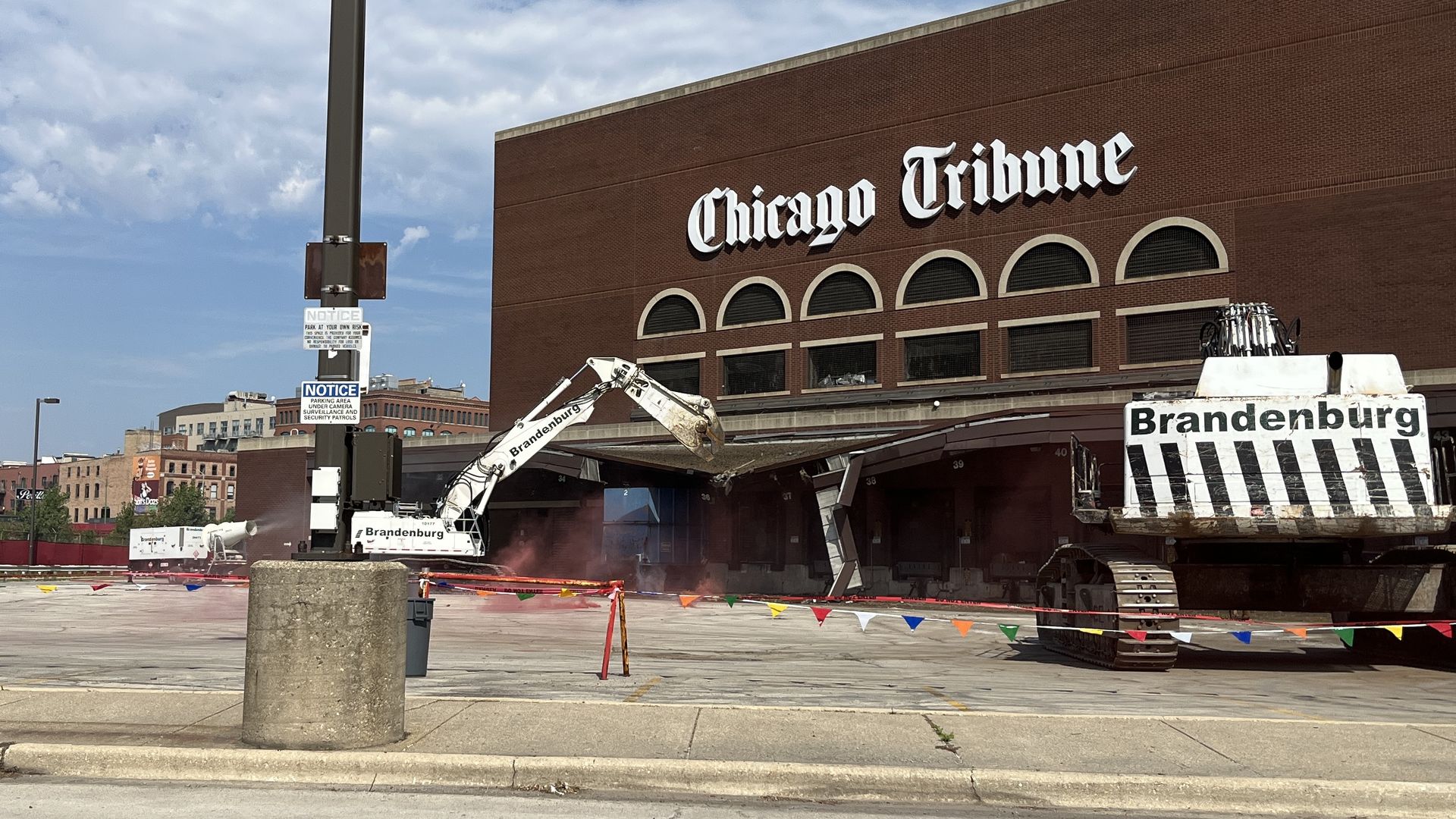 An excavator smashes into an old brown building with the words Chicago Tribune on it.