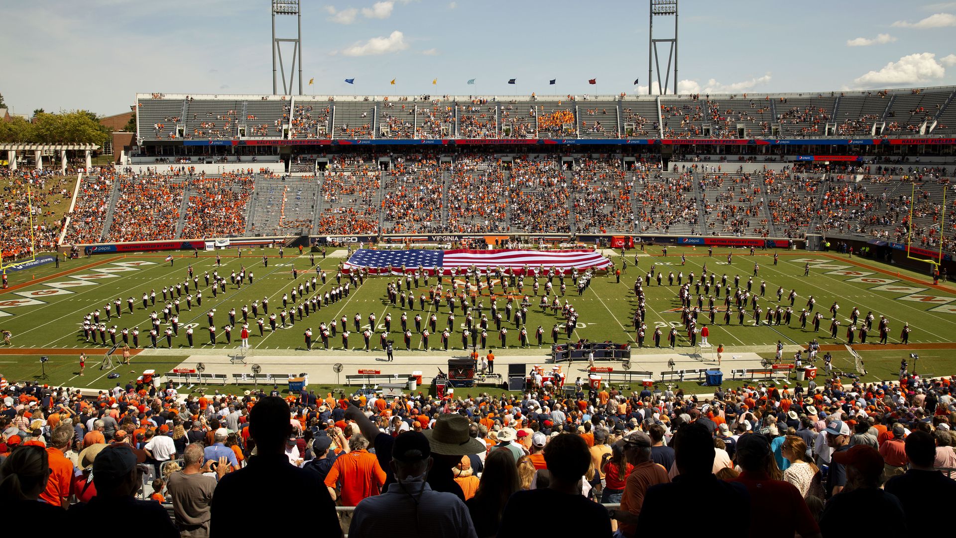 The Virginia Cavaliers marching band performs as an American flag is displayed to commemorate 9/11 at halftime during a game at Scott Stadium on September 11, 2021