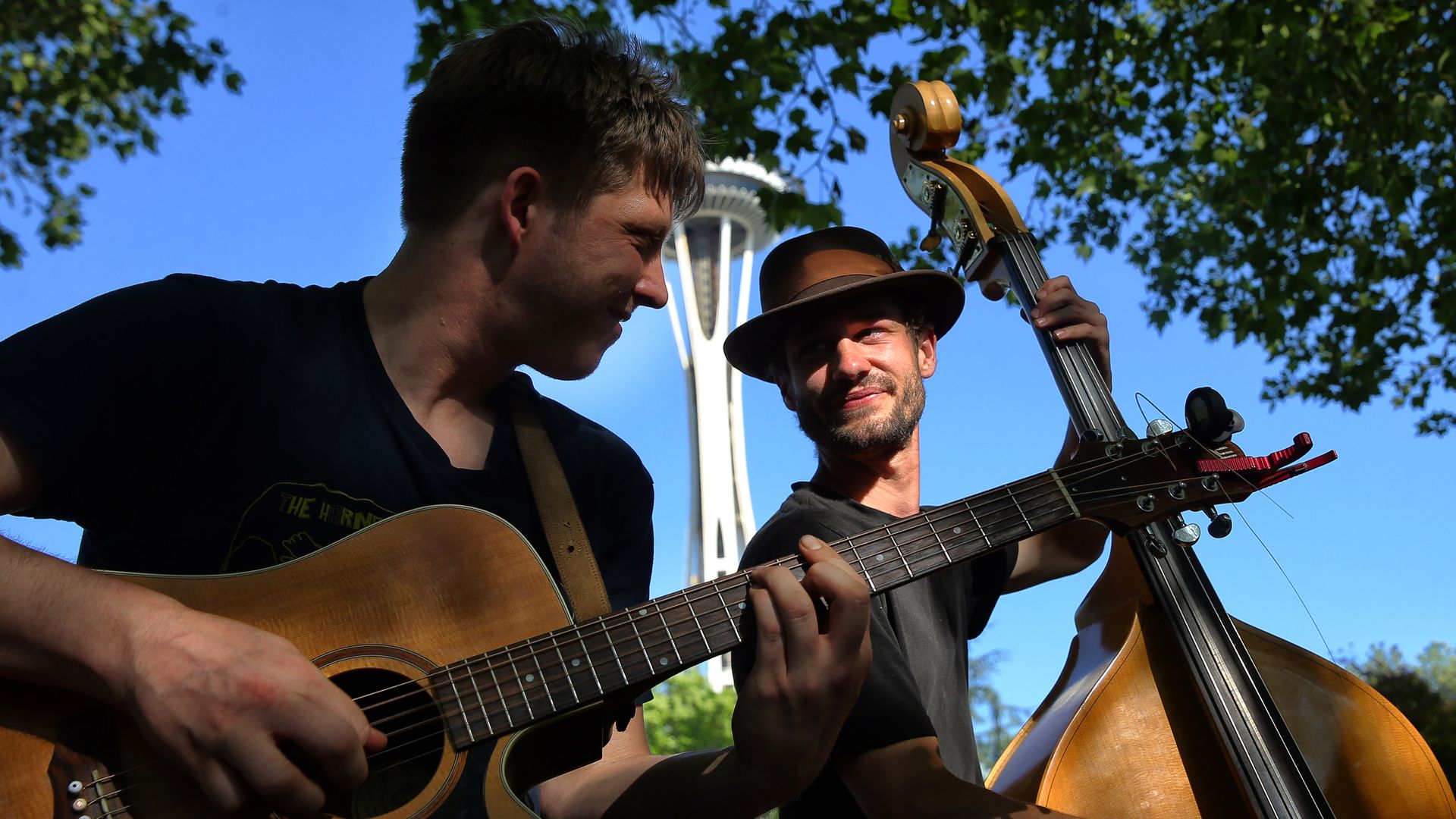 A guitarist and bassist jam in front of the Space Needle.