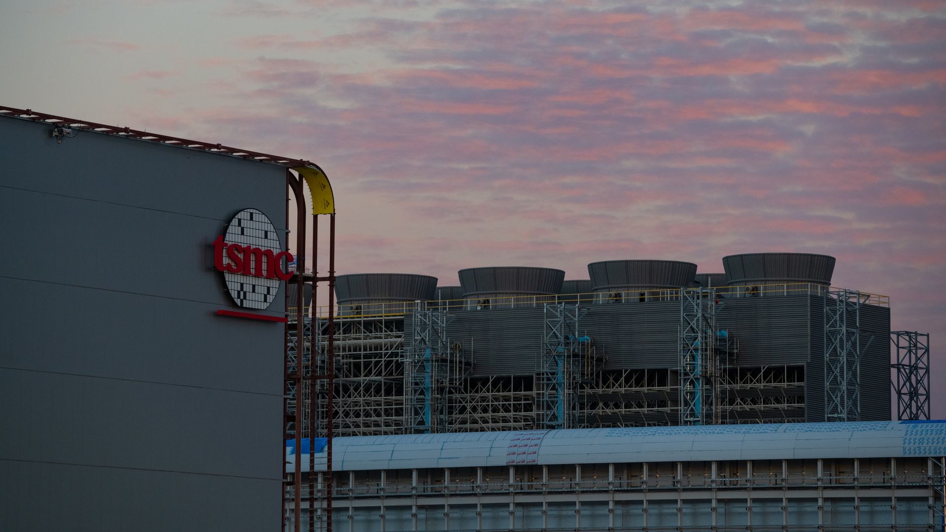 A partially constructed manufacturing plant with a sign that says TSMC.