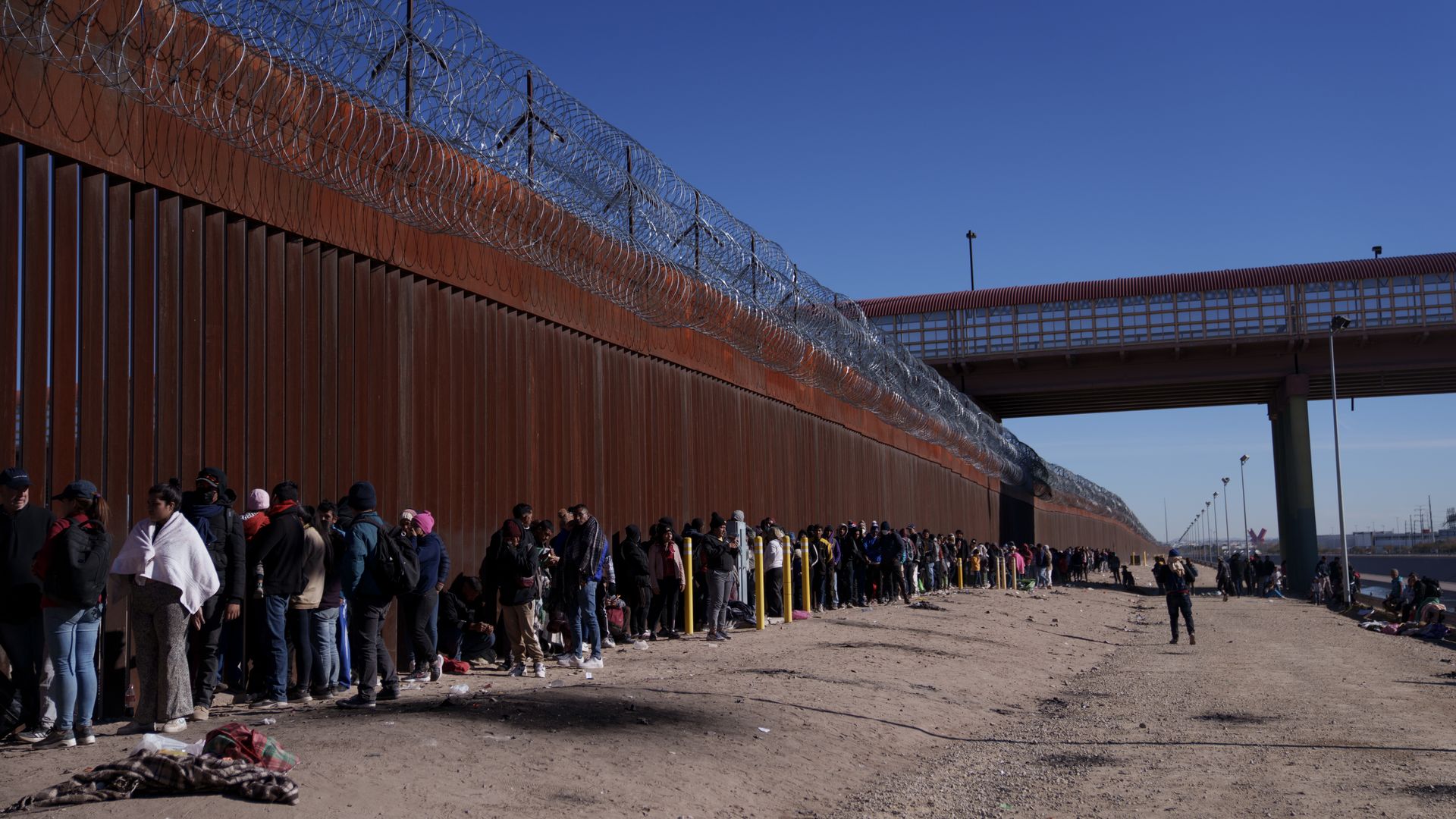 Migrants wait at the US and Mexico border wall in El Paso, Texas