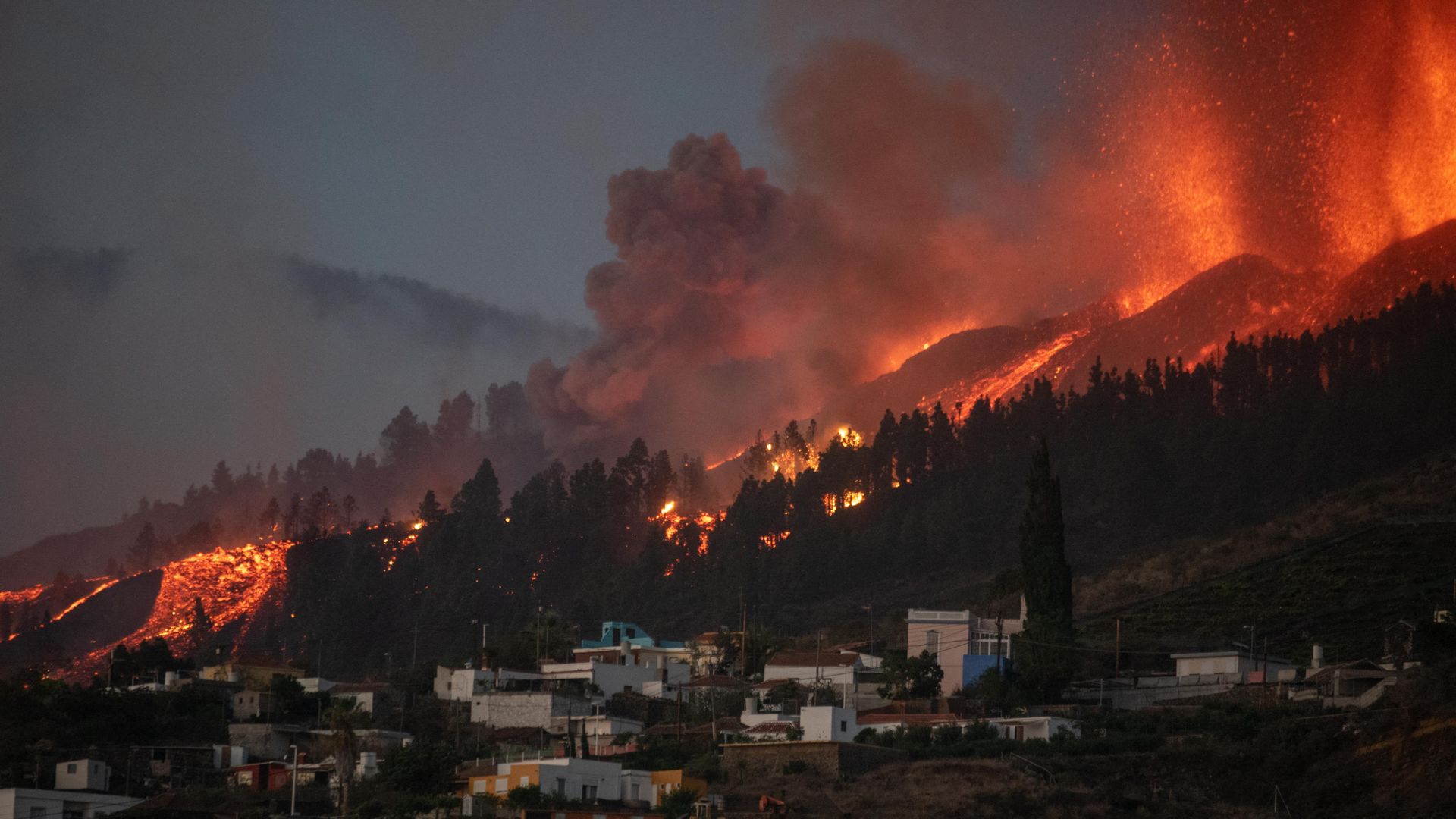 A river of lava approaches houses as Mount Cumbre Vieja erupts in El Paso, spewing out columns of smoke, ash and lava