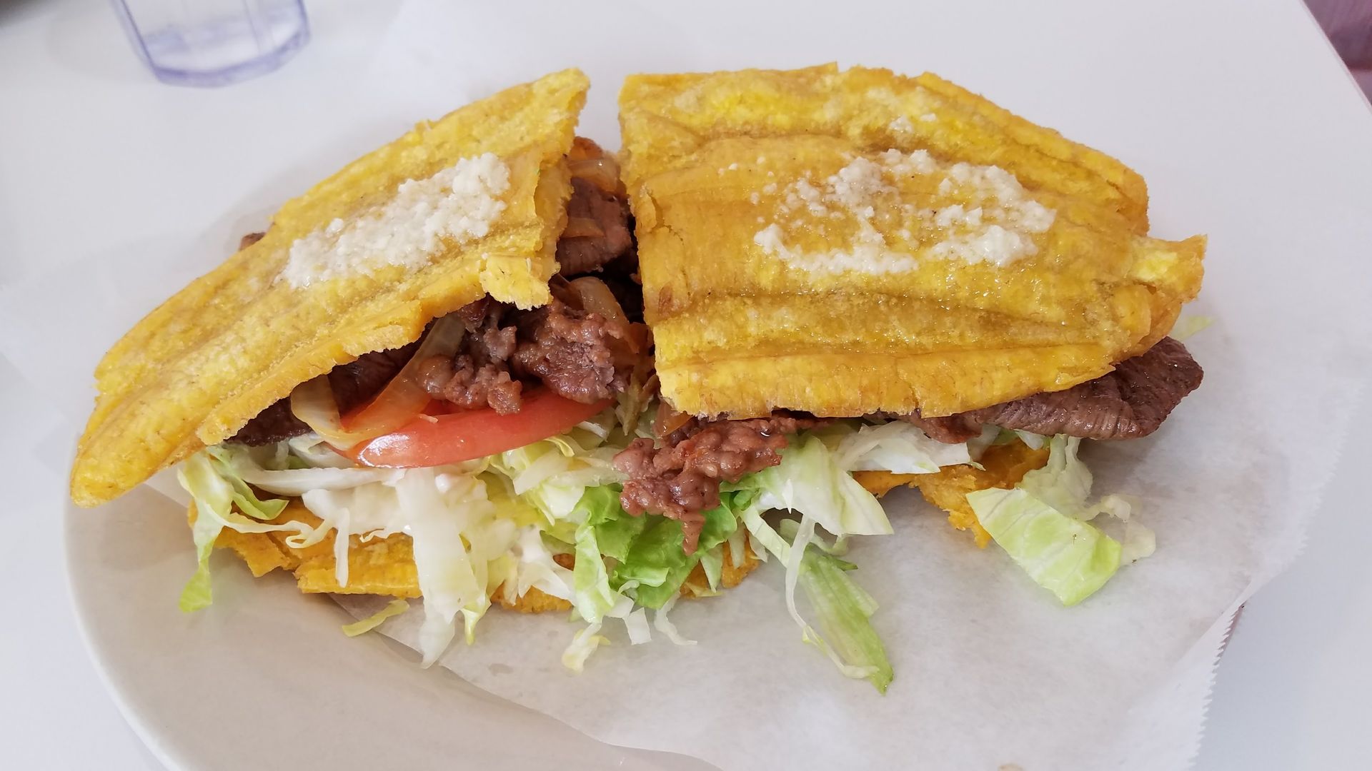 Sandwich with meat, lettuce and tomato inside slices of plaintain.