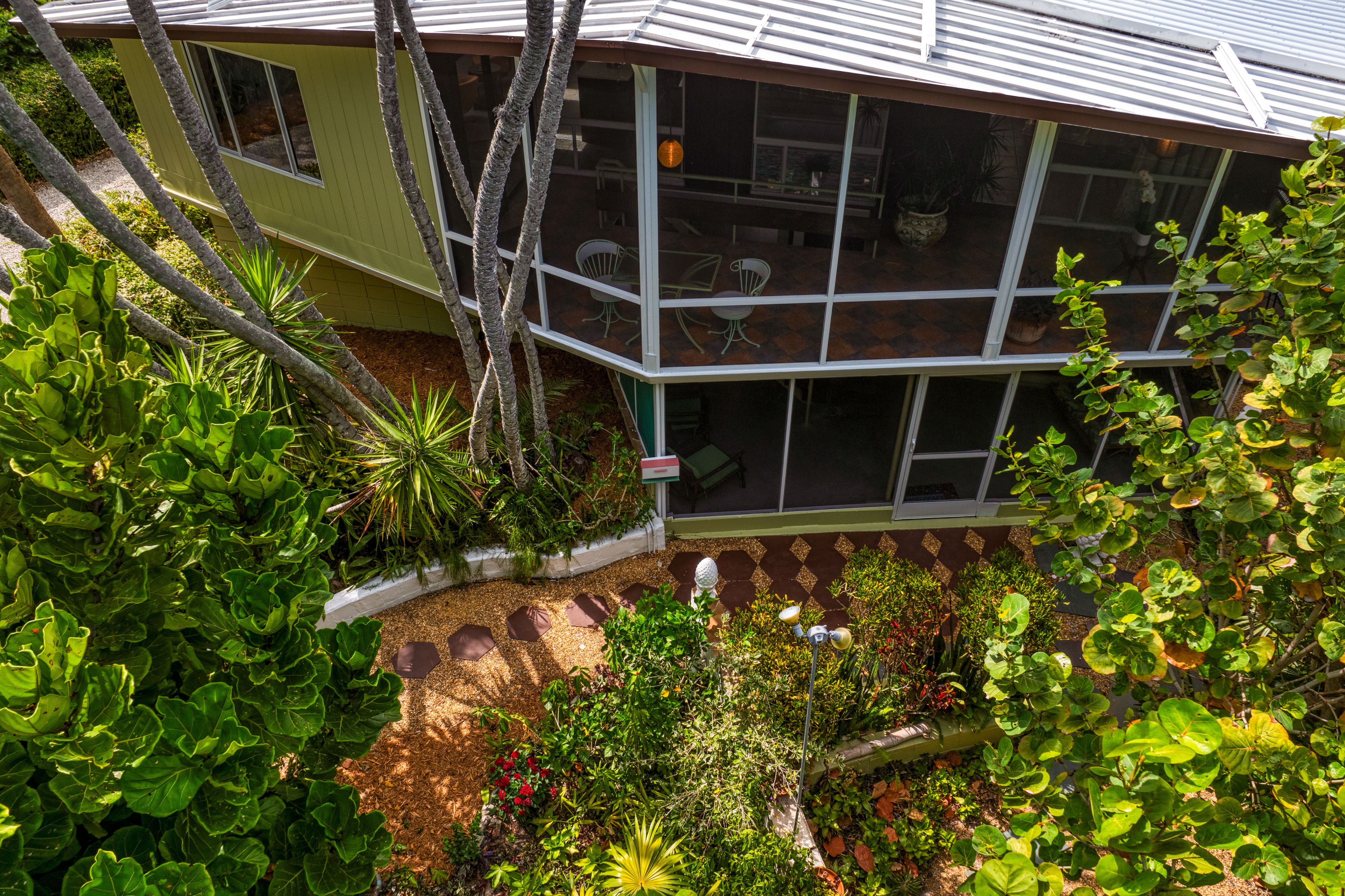 A two-story screened-in porch surrounded by lush greenery.