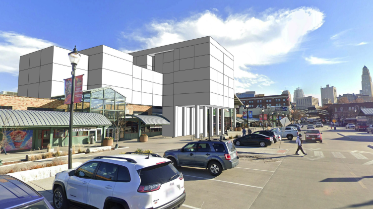 Rendering shows the east side of the City Market from Walnut Street including current ground-level retail and a white and gray shaded rendering of a blocky structure in place of the current steamboat museum, with cars parked in the foreground and the city skyline in the background.