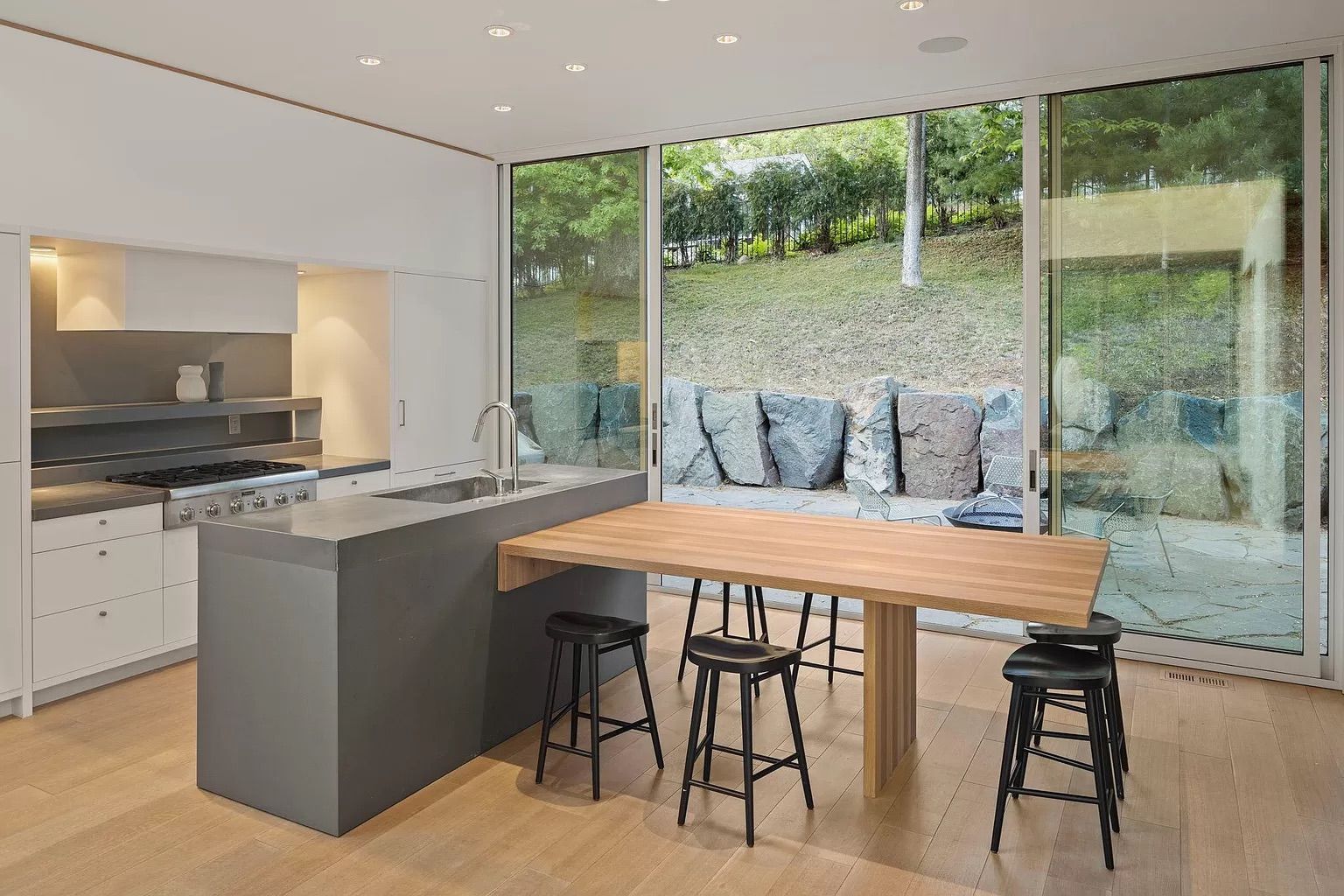 A kitchen with white cabinets and a wood table.
