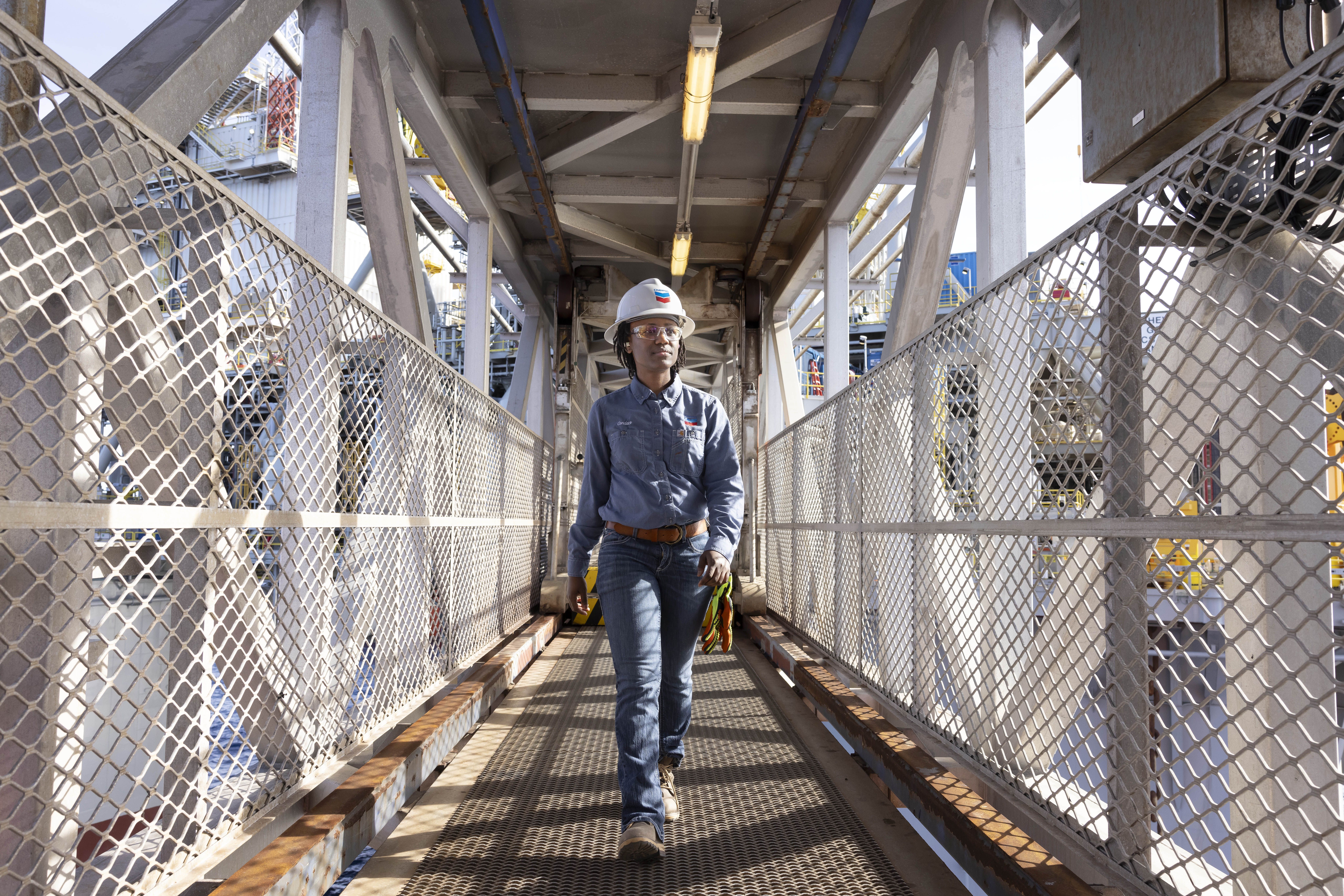 A woman in workgear walking through a gated walkway. 