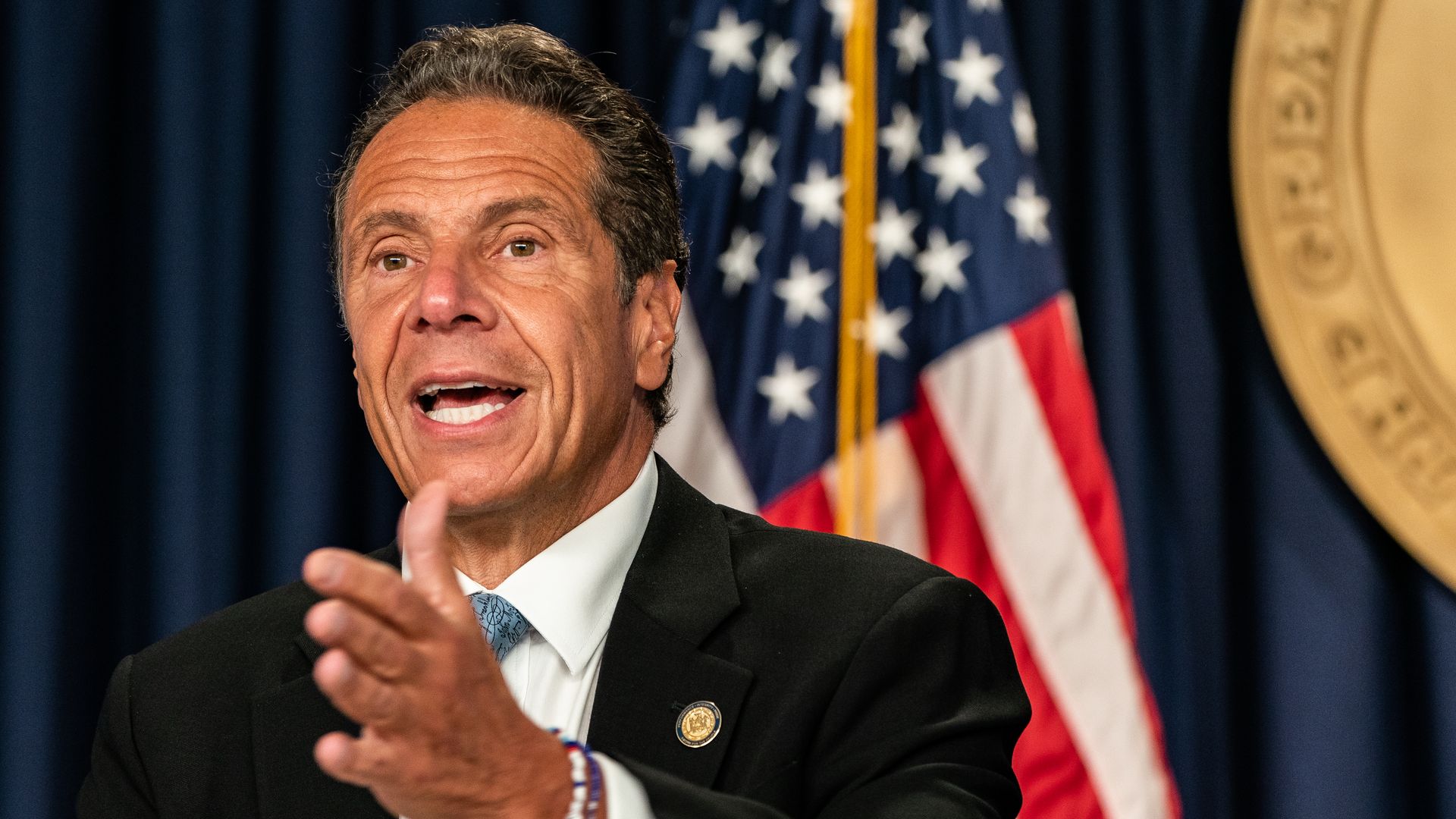 Andrew Cuomo sits in front of an American flag