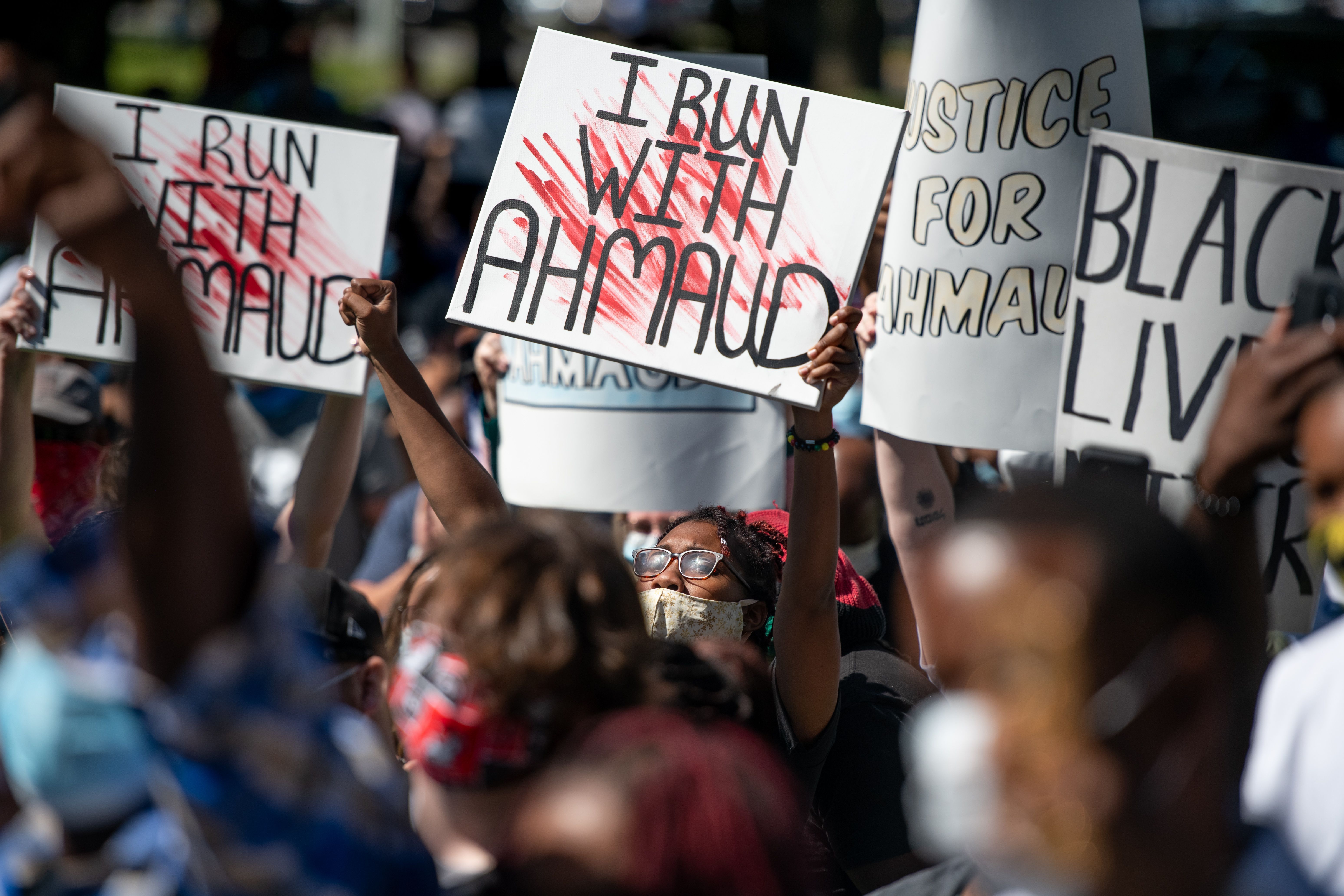 In this image, several people hold signs that read "I run with Ahmaud"