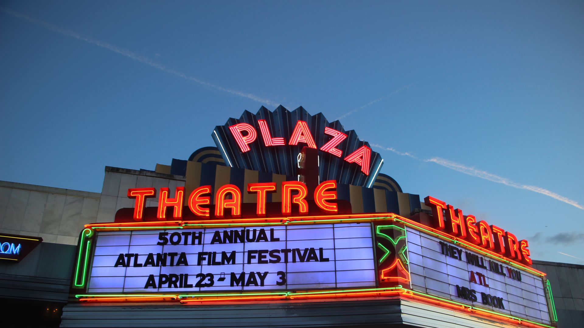 Neon Plaza Theatre marquee under a clear blue sky, with bright red "PLAZA" and "THEATRE" signs. The white marquee lists the "50th Annual Atlanta Film Festival" and dates April 23–May 3.