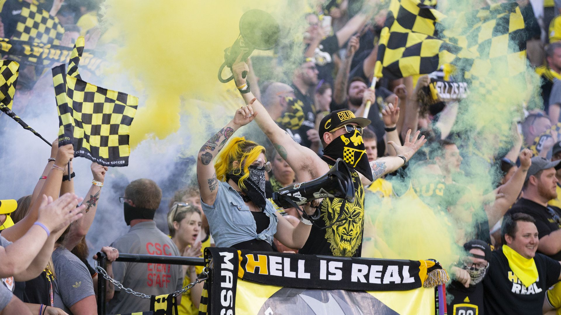 A Crew fan celebrates behind a "hell is real" sign