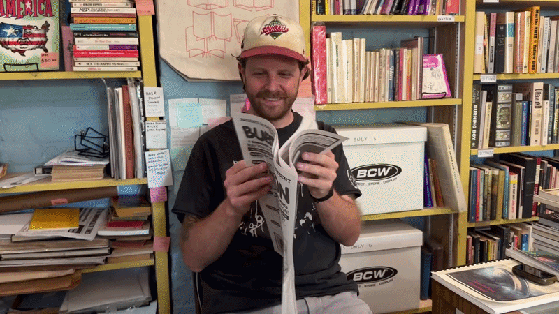 a video of someone in a bookshop opening up a newspaper