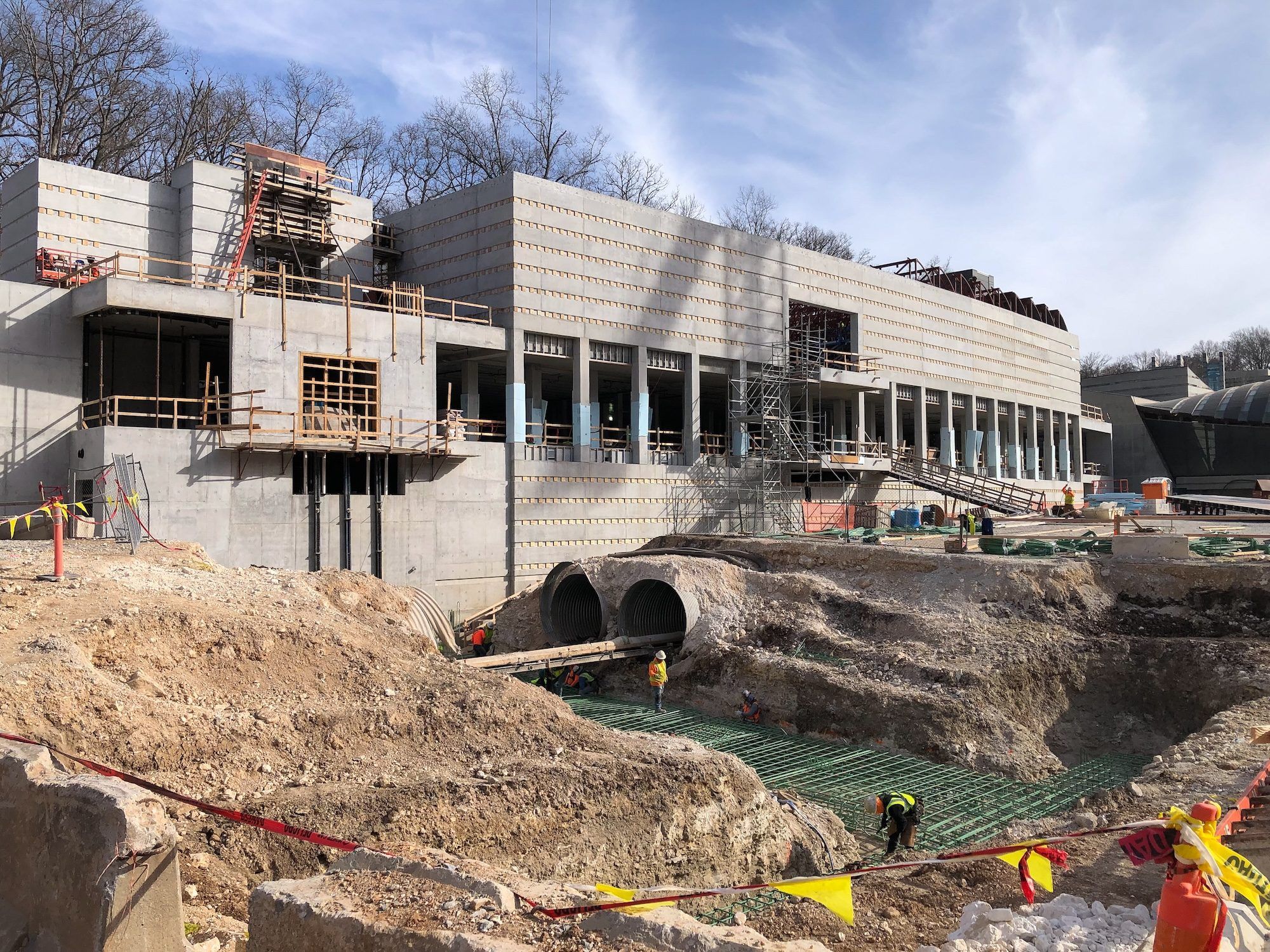 A photo of the a concrete building with workers all around. 
