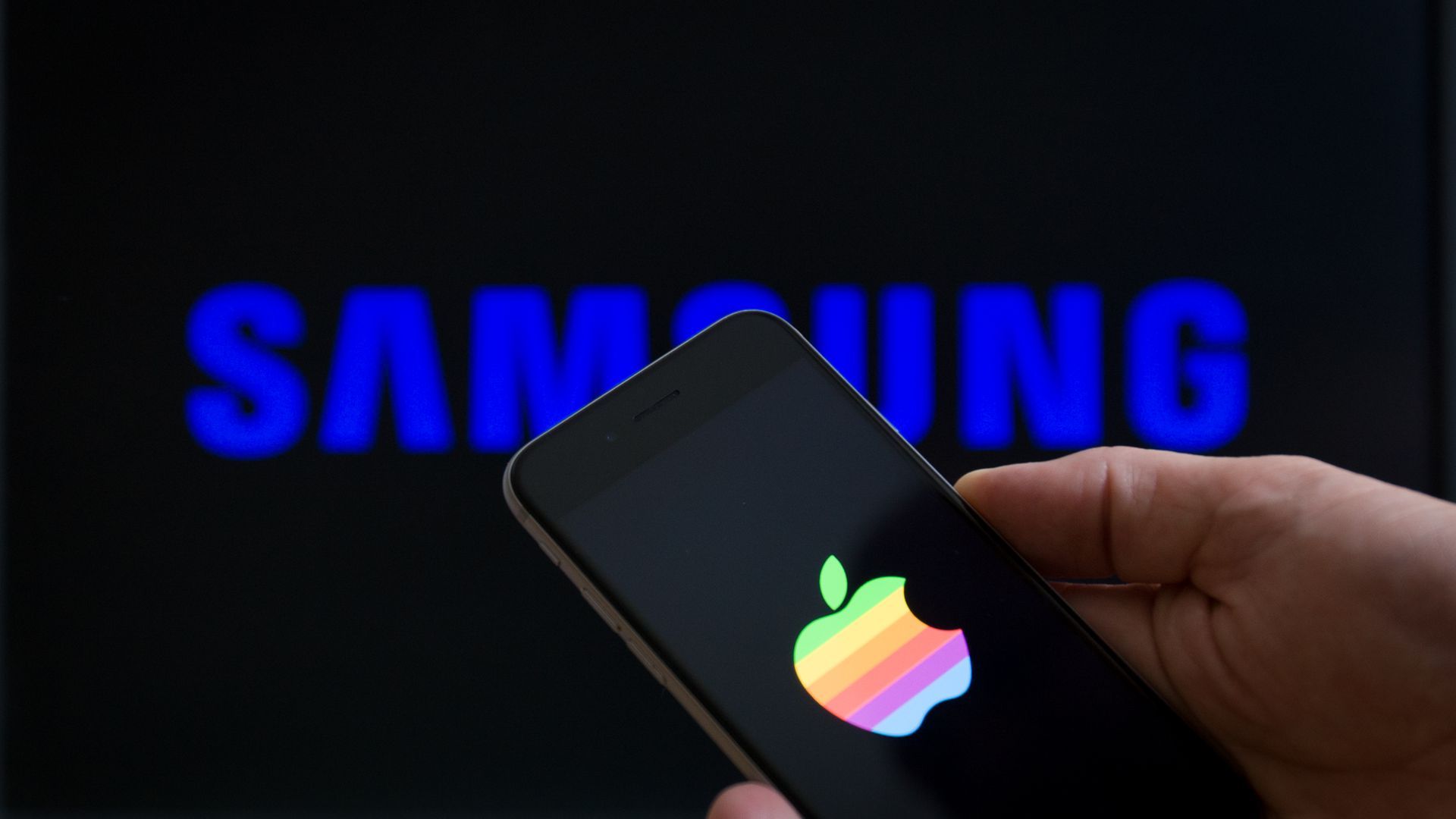 An iPhone poking through a Samsung logo