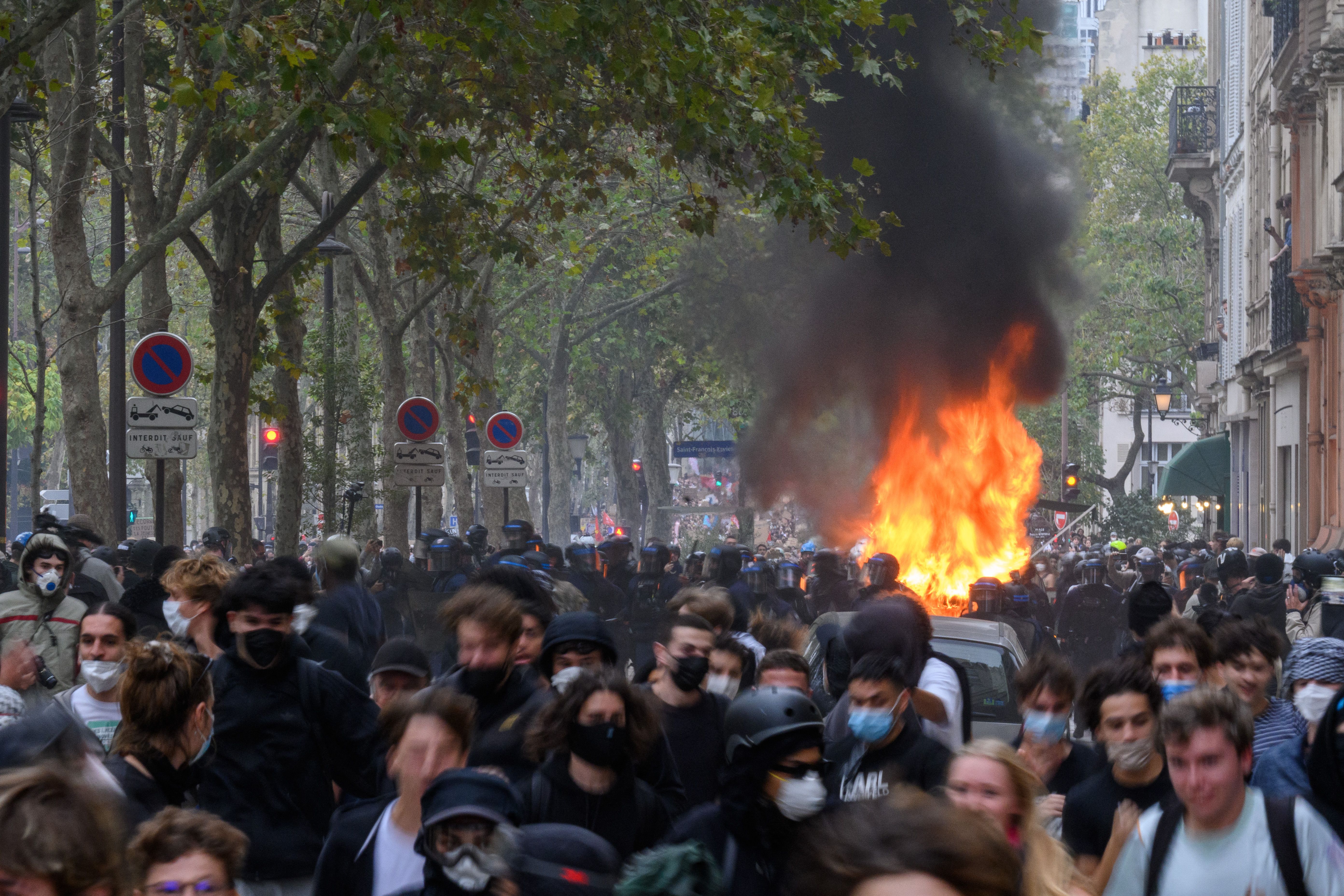 Police officers respond to a vehicle engulfed in flames during a large demonstration in Paris.