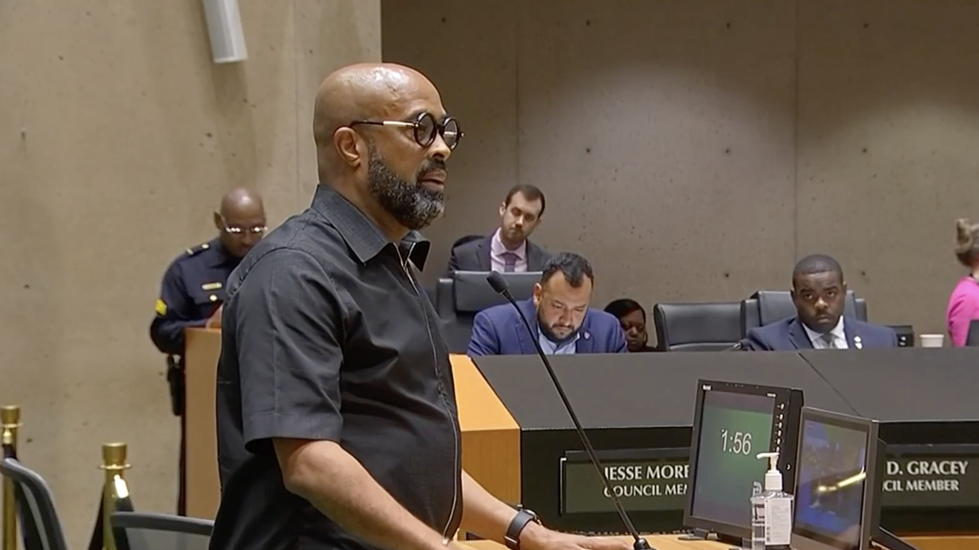 A man hovers over a microphone in a council meeting
