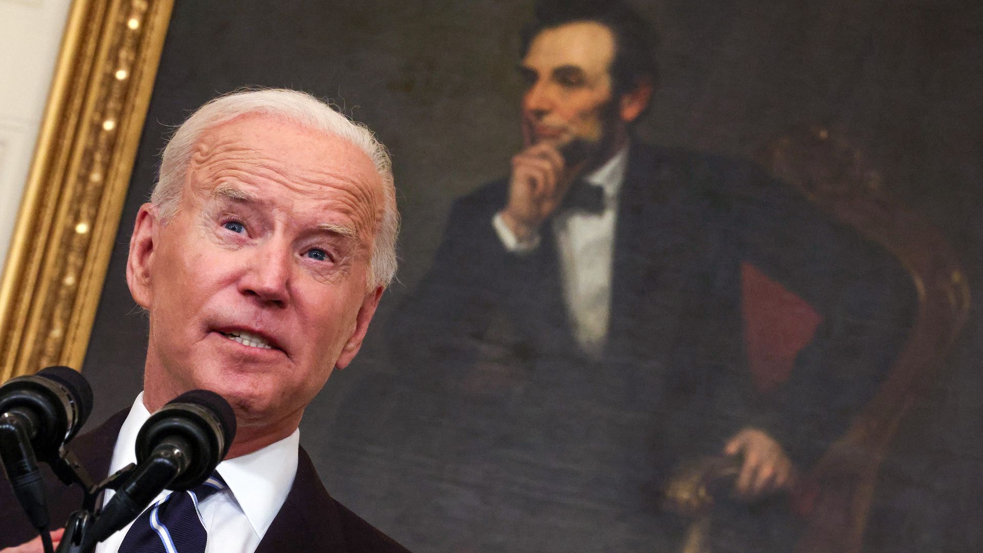 President Biden's face close up with Abraham Lincoln's portrait behind him