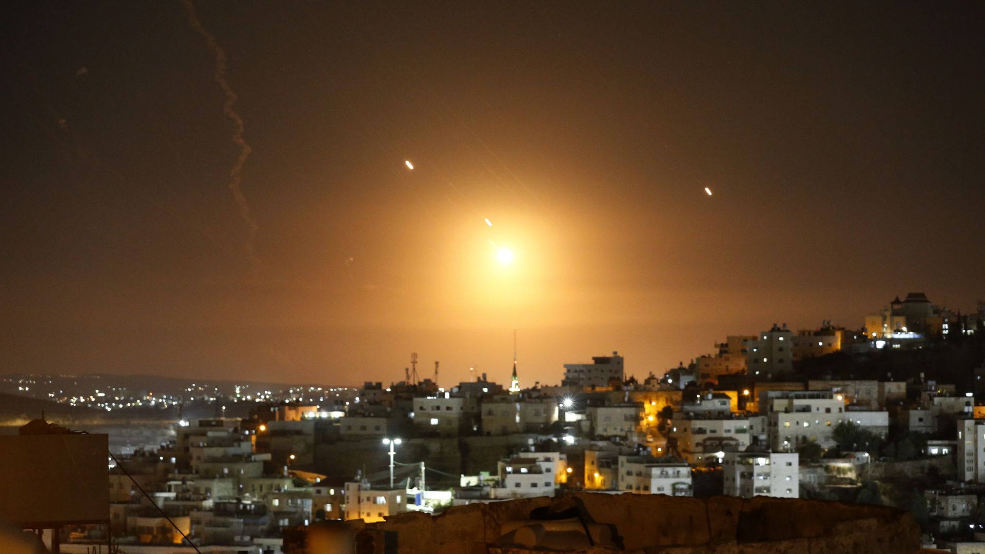 Rockets fired from Iran are seen over Jerusalem on Oct. 1. The sky is lit up orange. It's dark out, otherwise.
