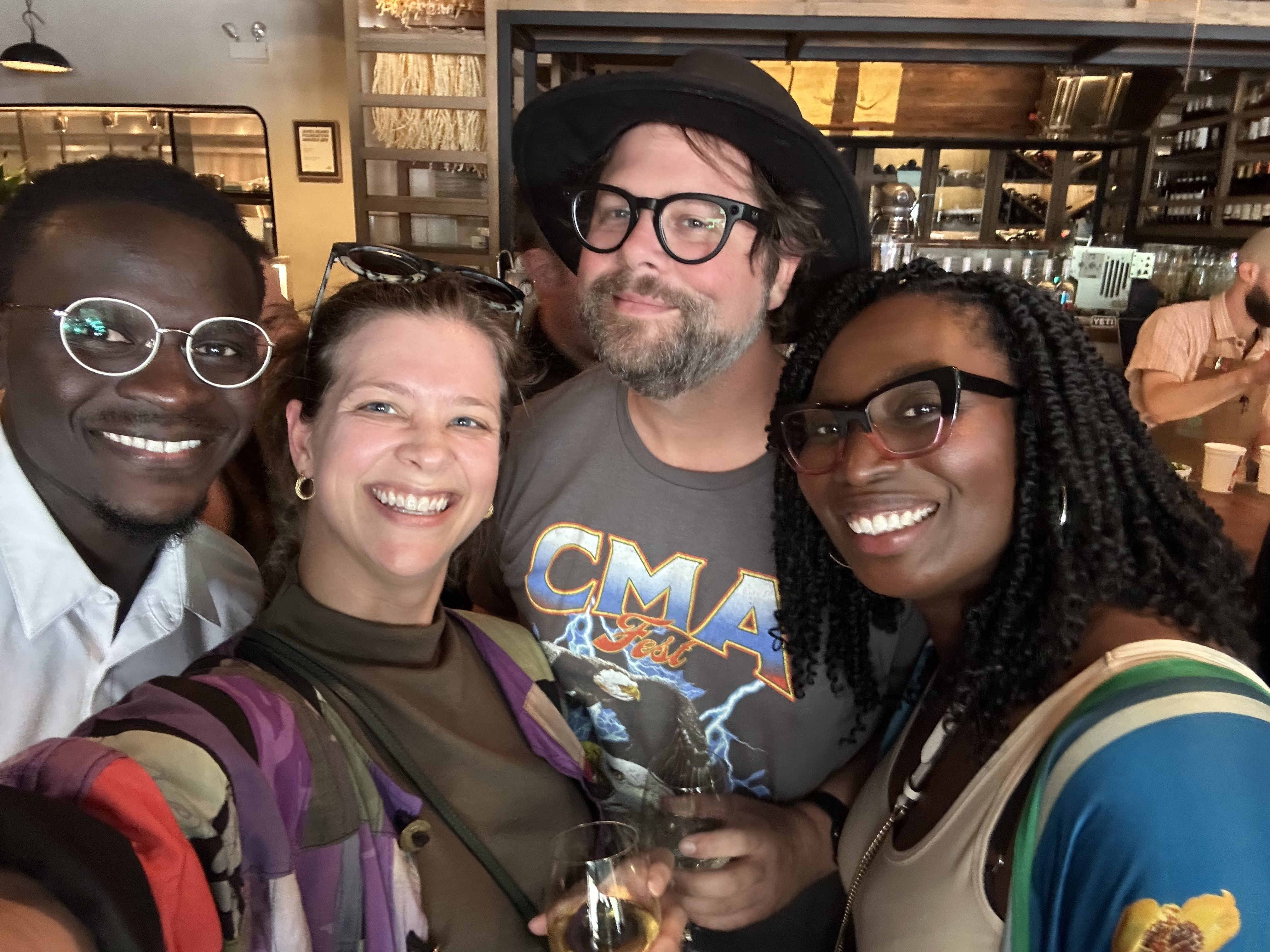 A selfie of four people smiling at the camera.