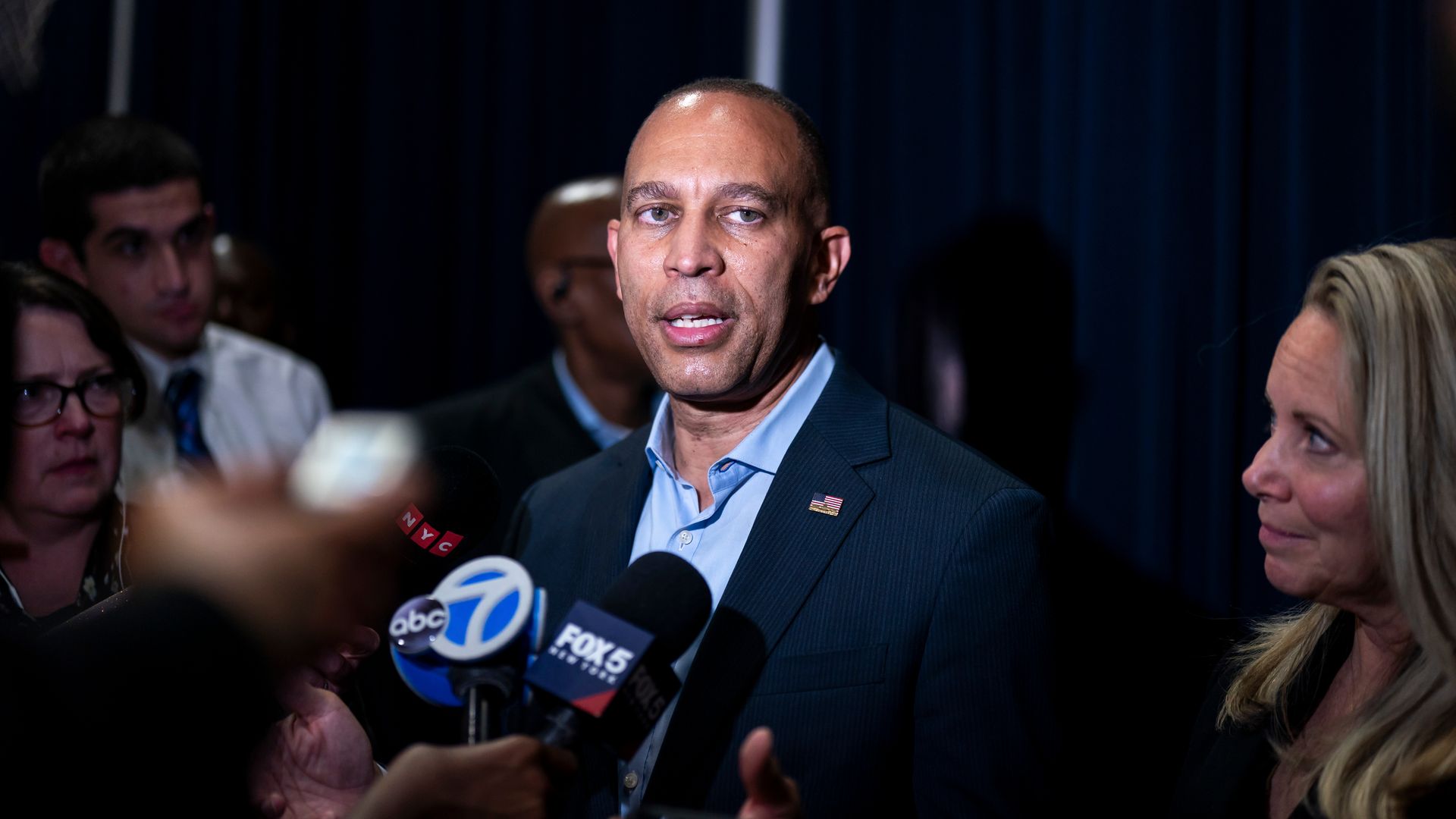 House Minority Leader Hakeem Jeffries wearing a blue suit and speaking into microphones.
