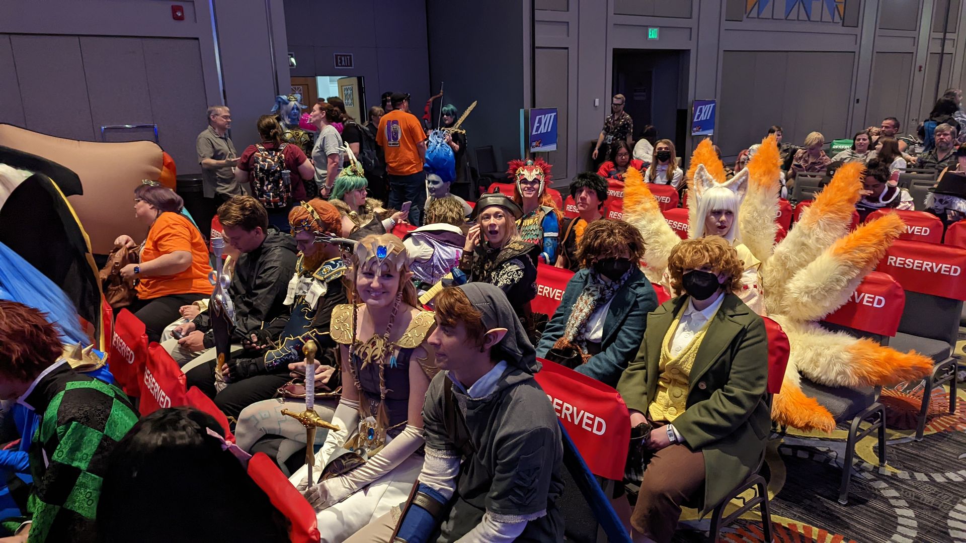 People in costumes sit in chairs in an auditorium.
