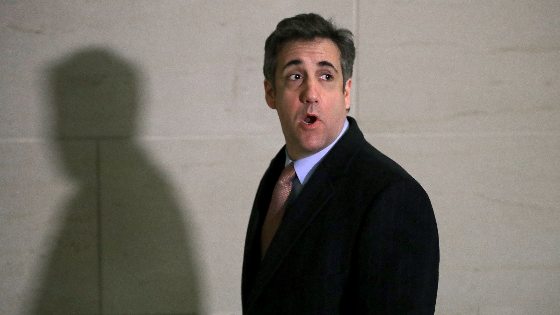 In this image, Michael Cohen looks behind him while looking surprised. 