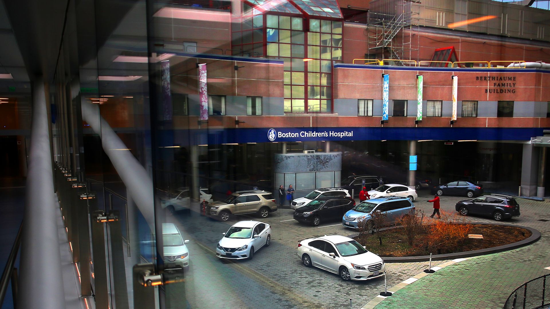 The view of the Boston Children's Hospital entrance from inside the building shows several cards in the parking lot.