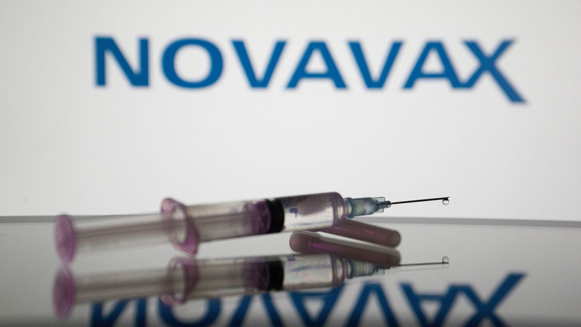 A syringe with the Novavax logo in the background.