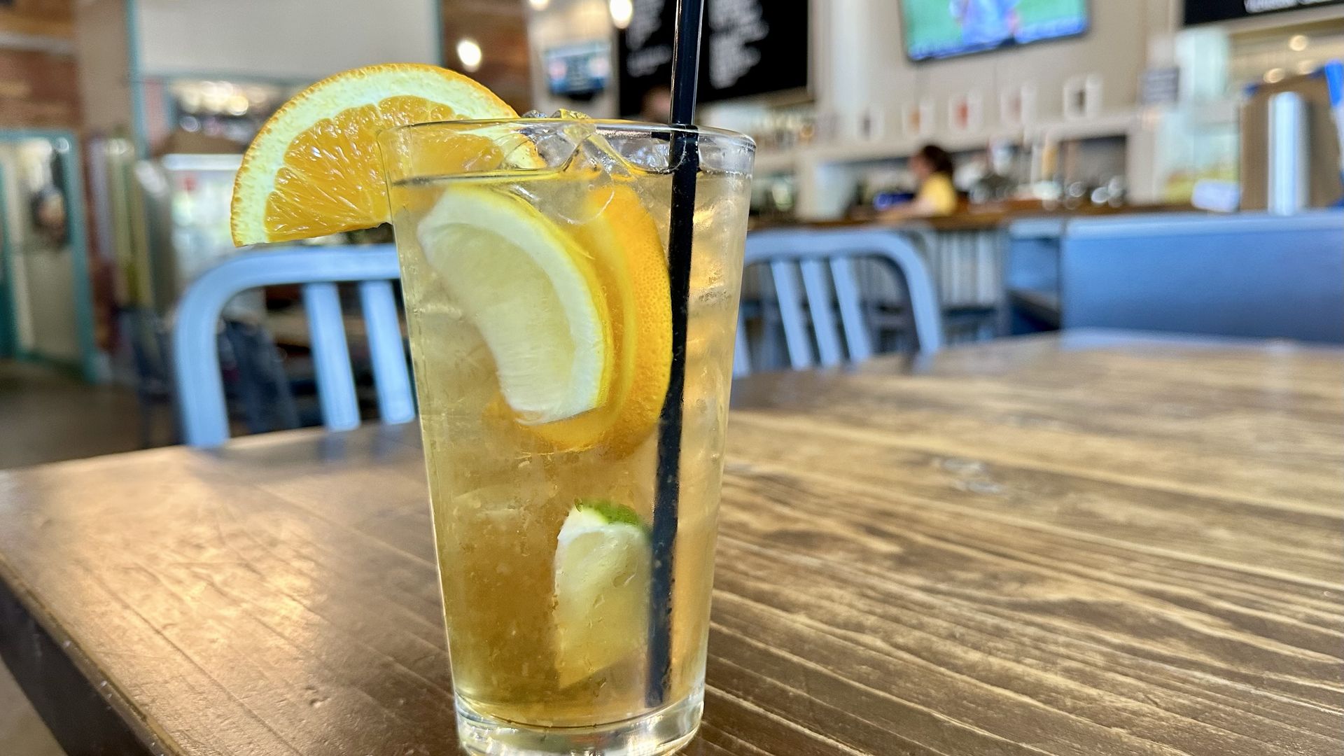 A photo of a cocktail in a tall glass filled with citrus fruit 