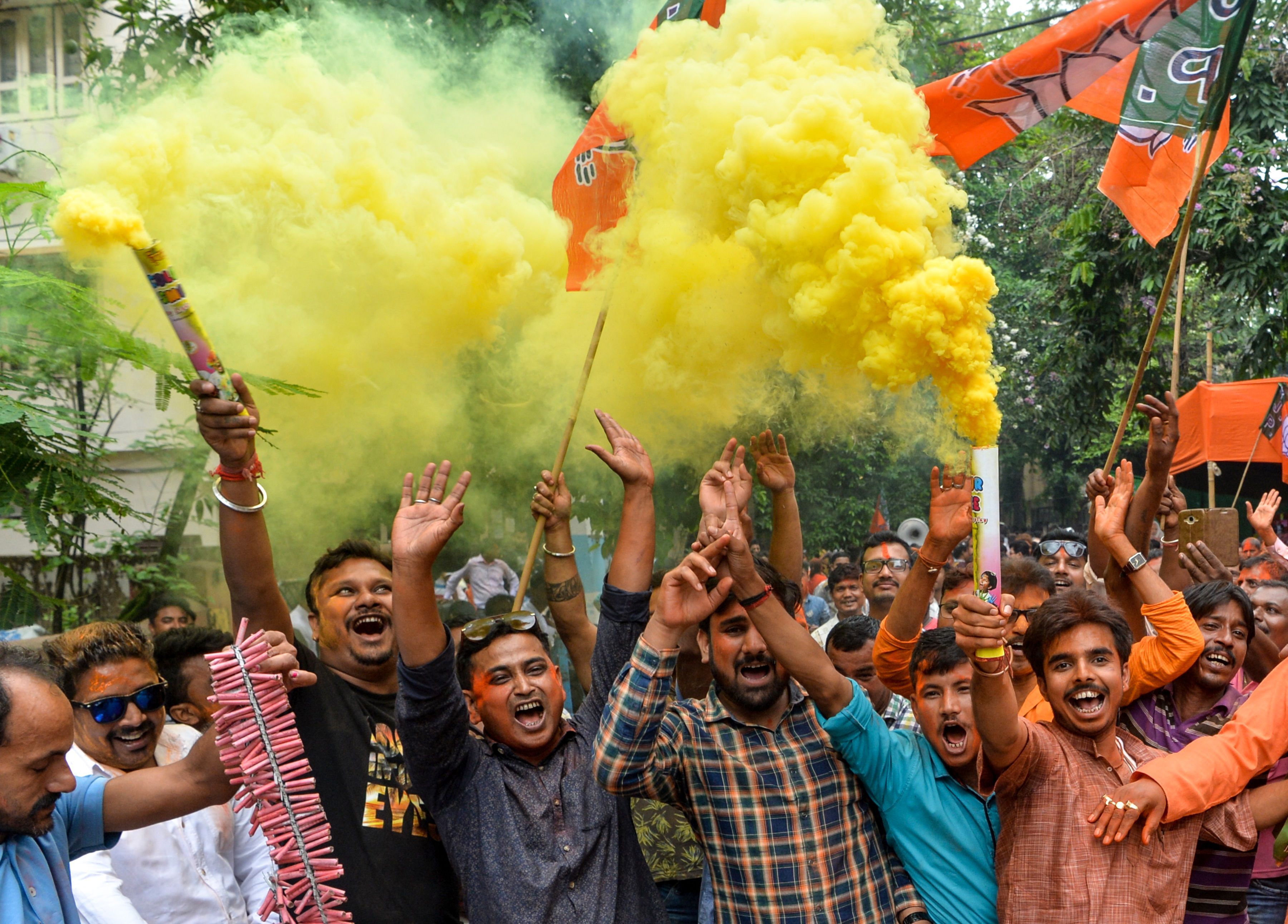 Indian supporters of Bharatiya Janata Party (BJP) hold colour smoke crackers as htey celebrate on the vote results day for India's general election in Siliguri on May 23, 2019. 