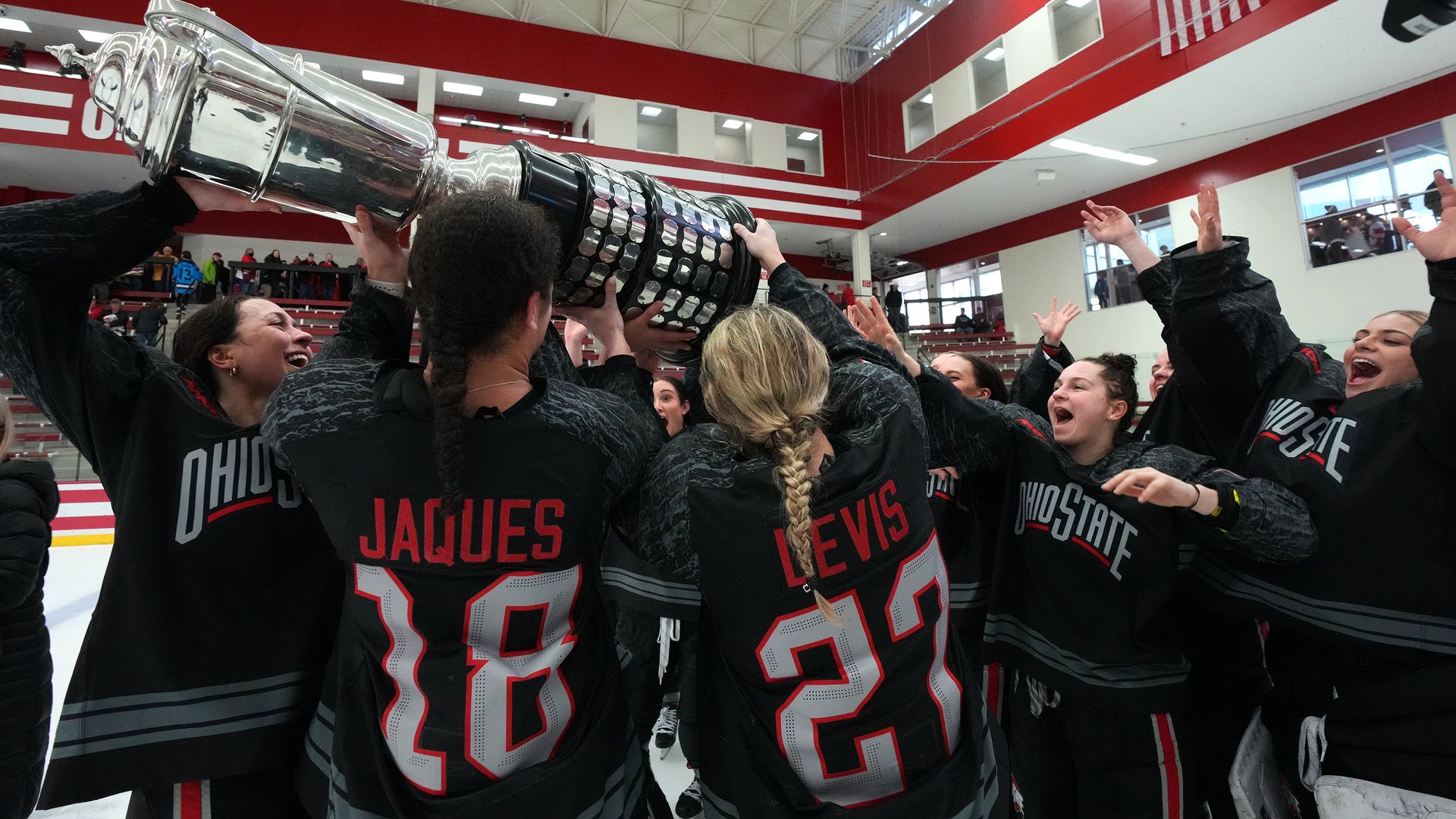 Ohio State women's hockey players hoist a trophy after winning the conference title. 