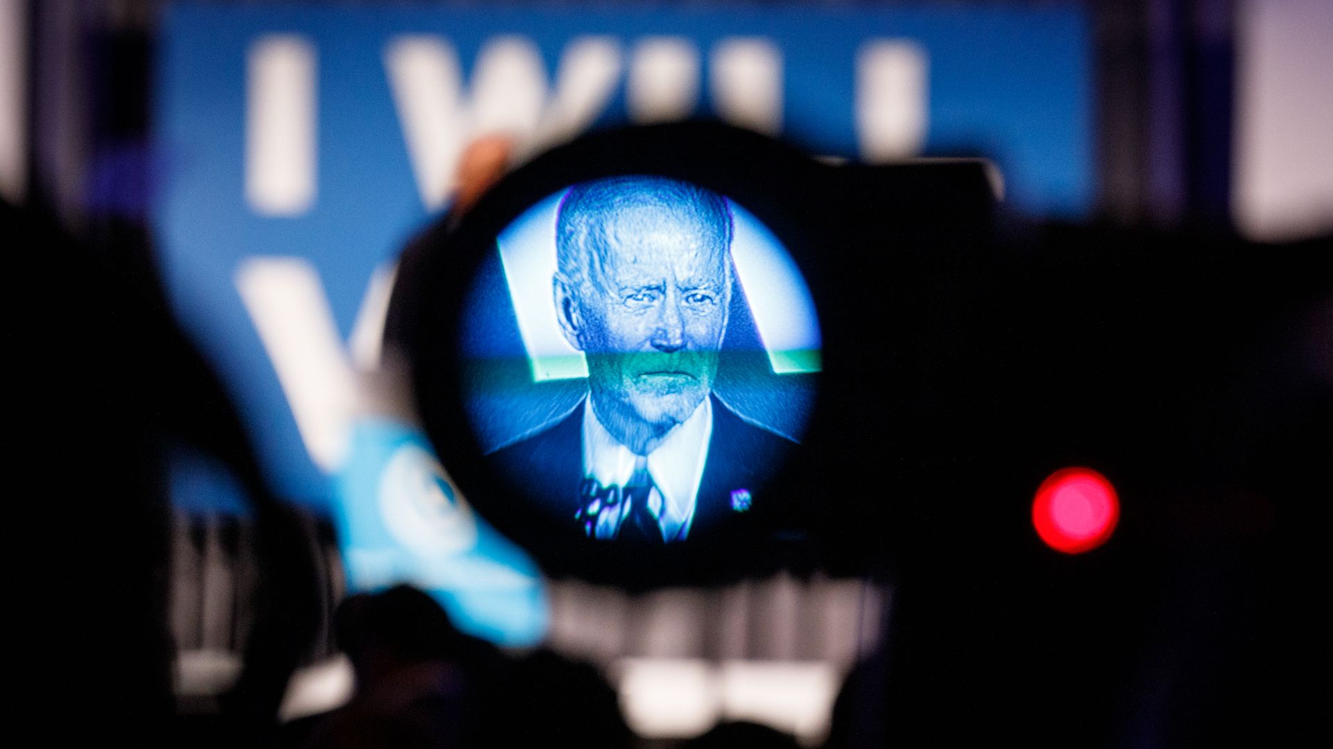 In this image, Biden is seen in a blue filter on a TV camera as he's being filmed while speaking on stage.