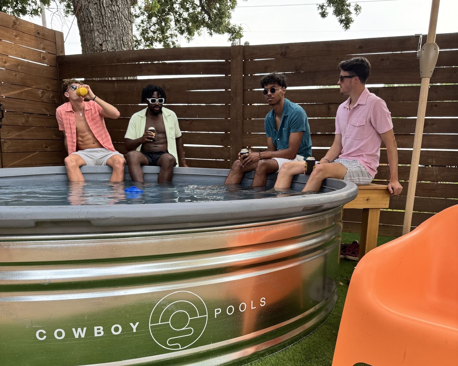 A photo of four people sitting on the edge of a stock tank pool.