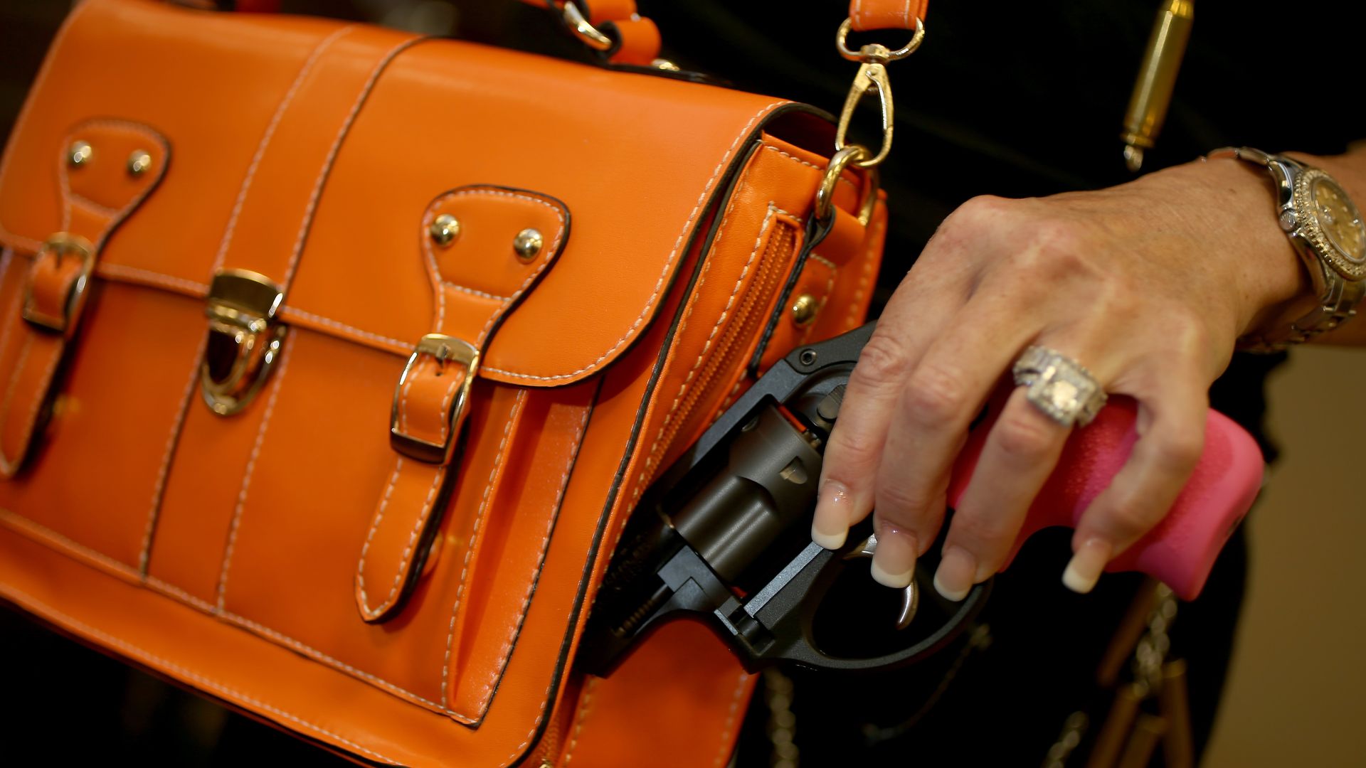 Woman holds gun next to purse.