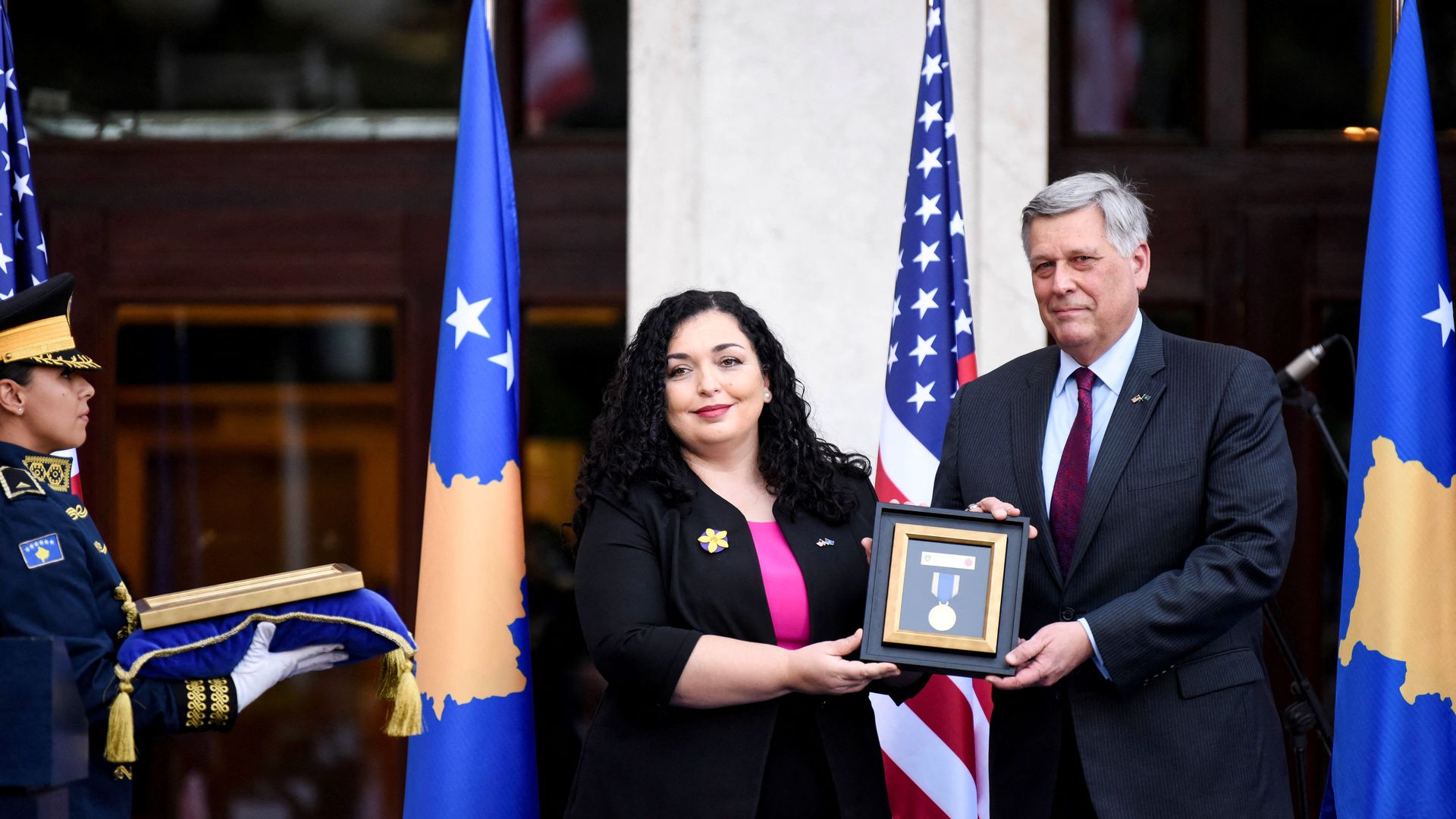 Kosovo's President Vjosa Osmani hands over a medal to US ambassador Philip Kosnett 