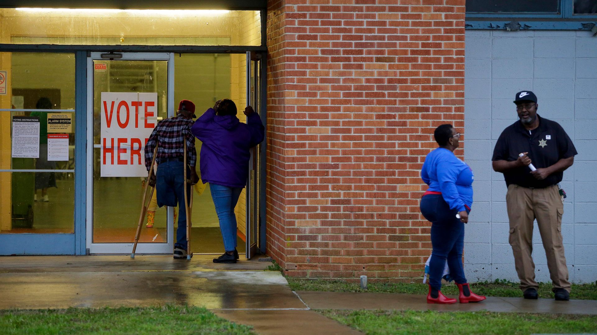 Voters stand in line behind a "vote here" sign in Alabama