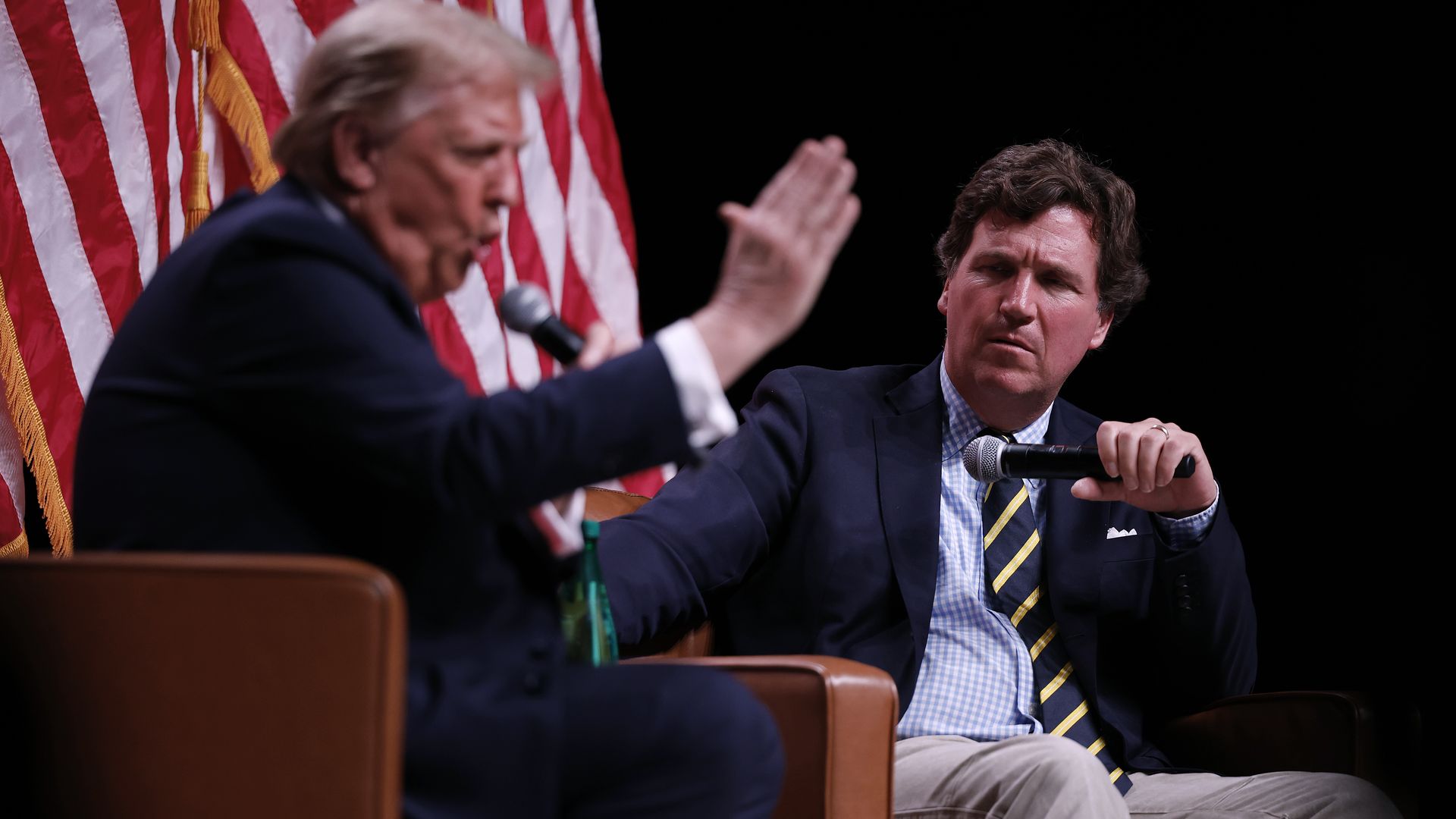 Donald Trump sits across from Tucker Carlson during an onstage conversation at Desert Diamond Arena.