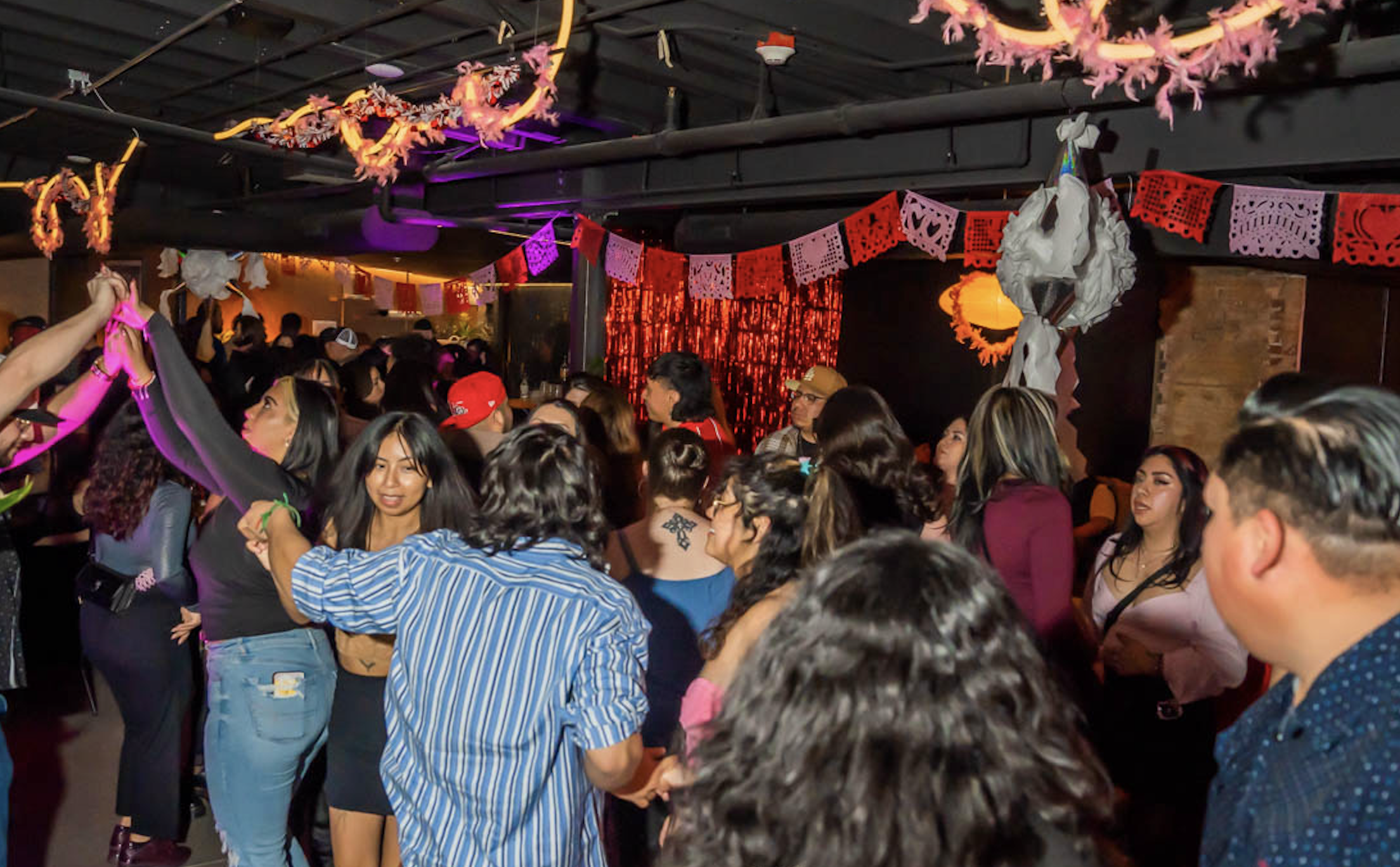 People dance at a crowded bar.
