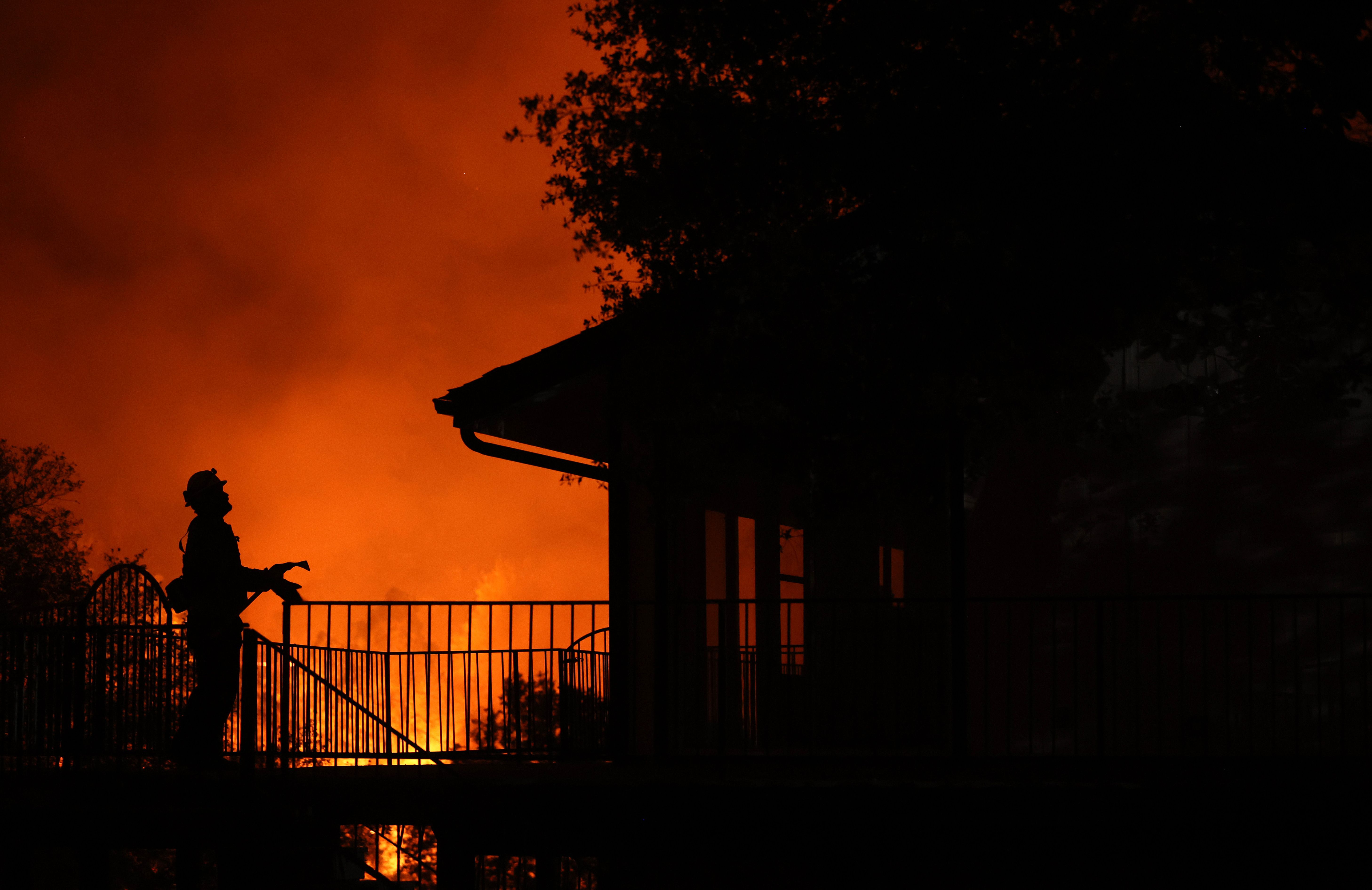 A firefighter stands on the deck of a home as the Oak Fire moves through the area on July 23, 2022 near Mariposa, California. T