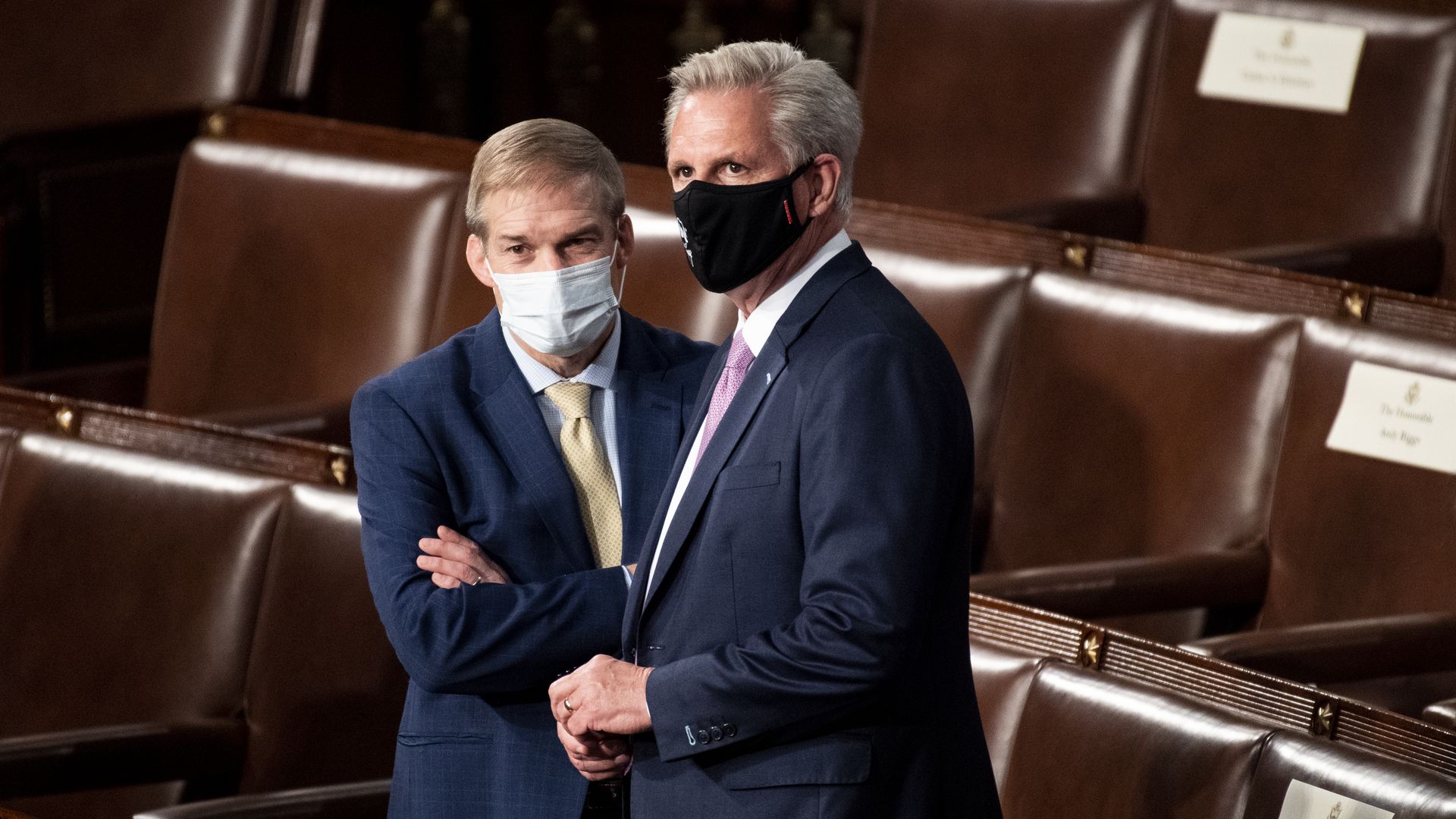 Reps. Jim Jordan and Kevin McCarthy stand in the House chamber wearing masks.