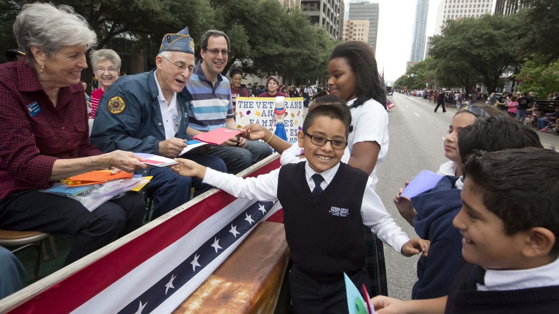 Elementary school aged children give out hand-made cards to military veterans during the Veteran's Day parade down Congress Avenue.