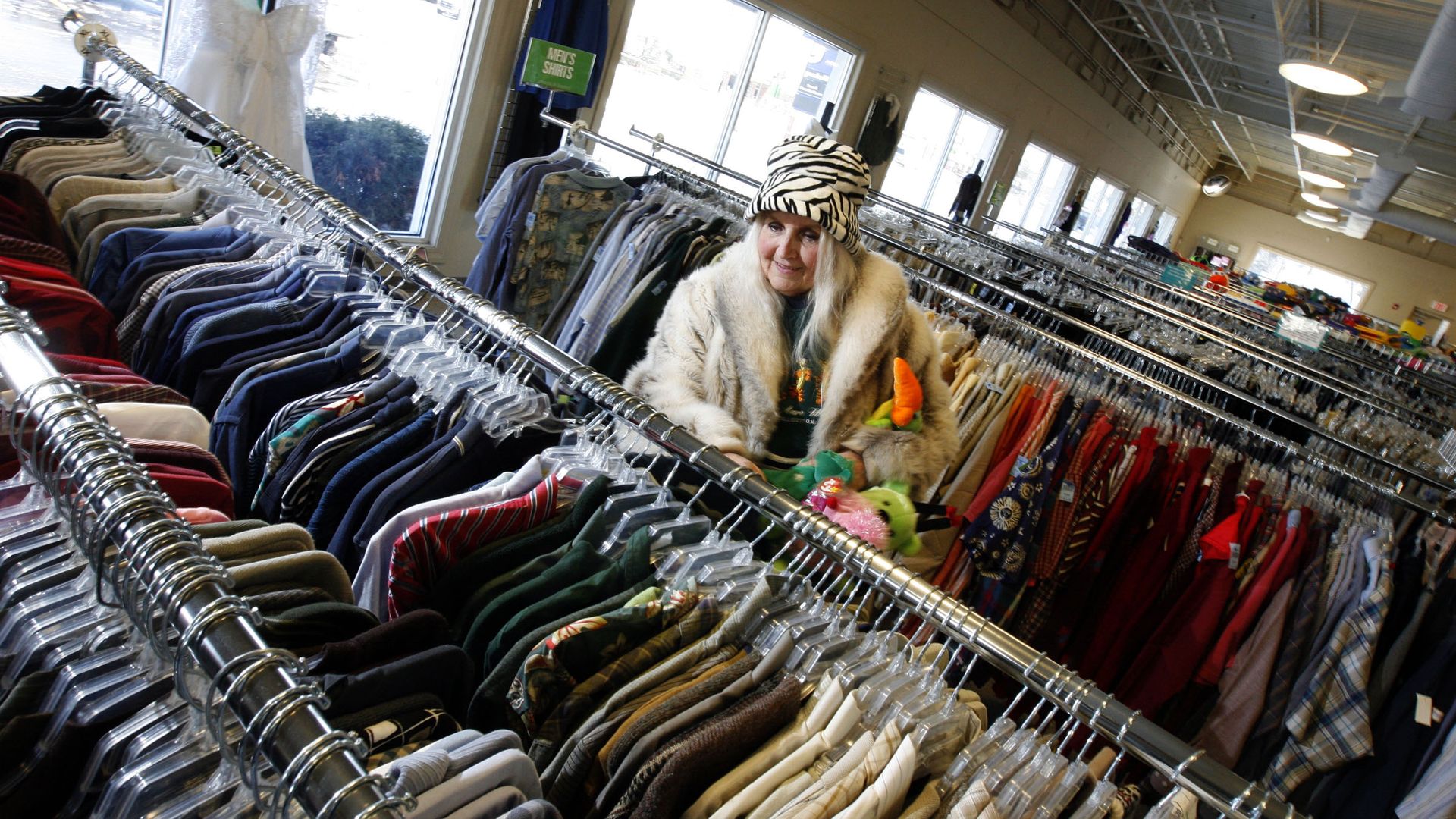 Photo of a woman shopping through racks of clothes. 